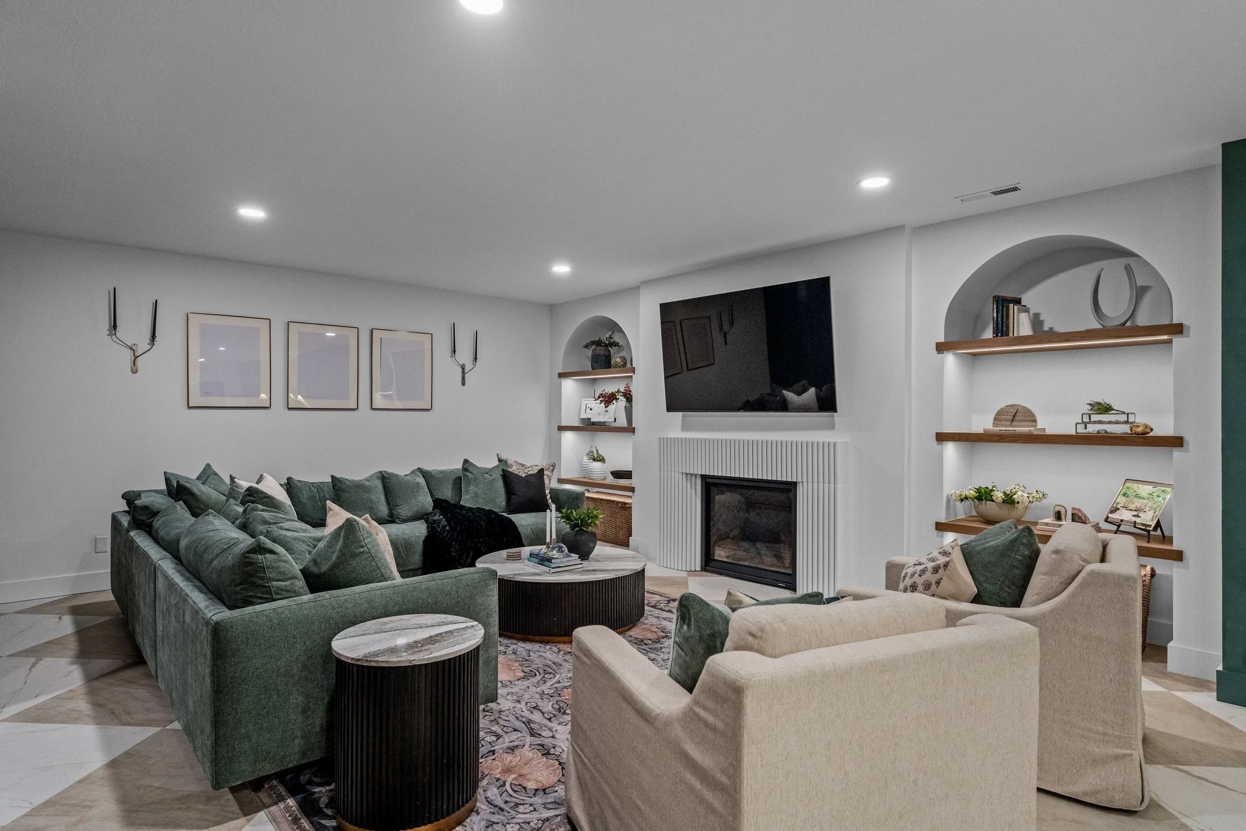 Finished basement living room in Centerville, Ohio with a green sectional, gas fireplace, and custom arched built-ins by White Oak Interiors