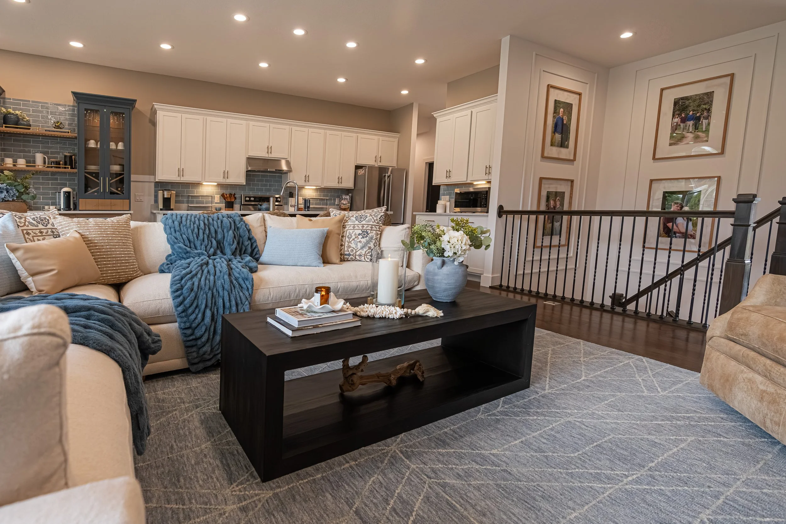 Living area with a cream sectional beside the staircase, open to the white kitchen in a Centerville home renovation.