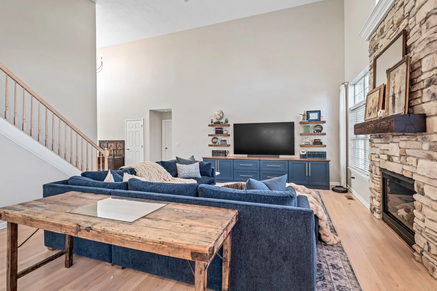Living room with a navy blue built-in media console, blue sectional, and vaulted ceiling in a Beavercreek, Ohio main-level remodel.