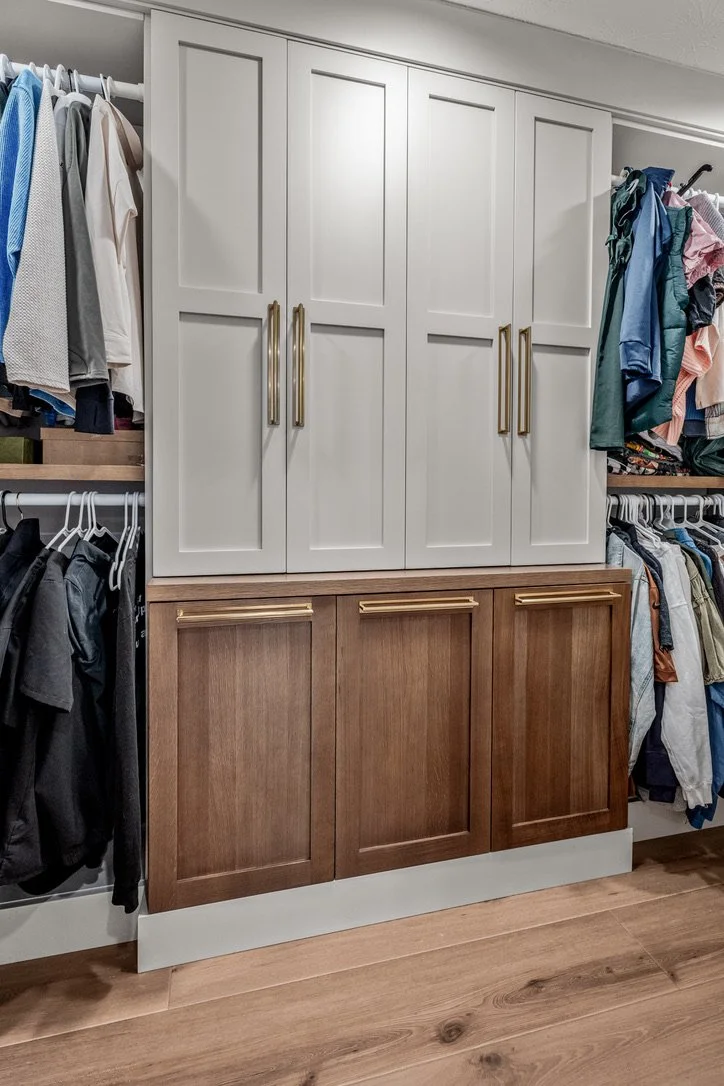 Custom walk-in closet with built-in white cabinetry, wood drawers, gold hardware, and double-hung clothing storage in a Xenia, Ohio master suite