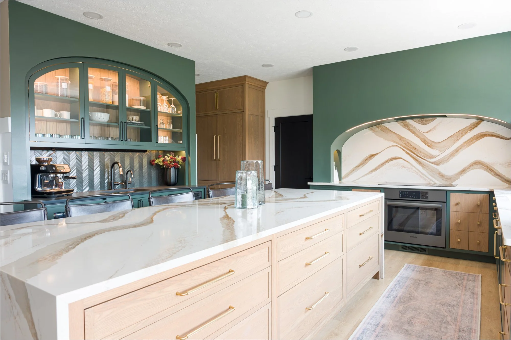 Custom kitchen design near Dayton, Ohio with a white oak island, glass-front display cabinetry, and herringbone tile detailing by luxury interior designer White Oak Interiors.