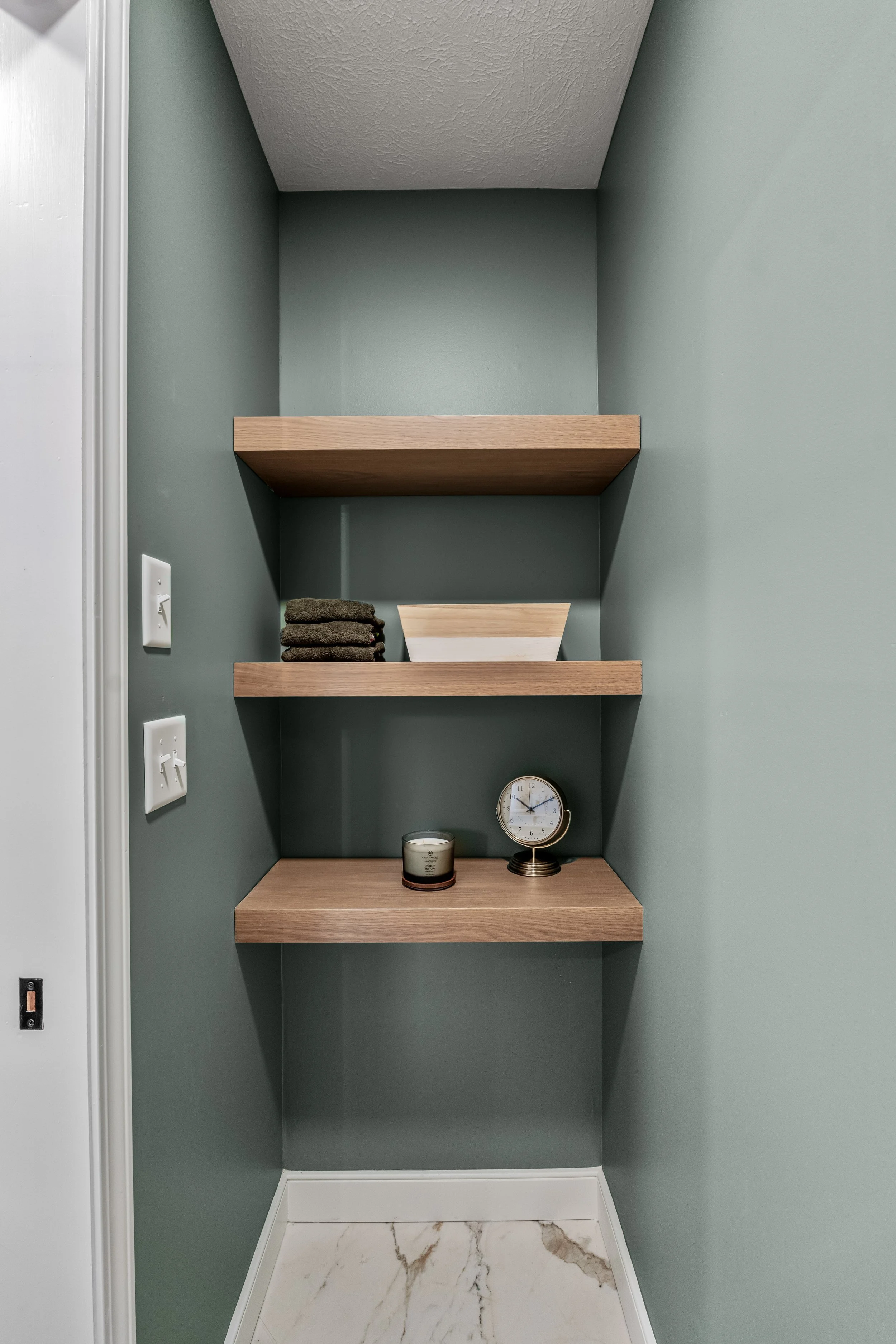 Basement bathroom in Centerville, Ohio with built-in wood storage shelving and evergreen fog walls by White Oak Interiors