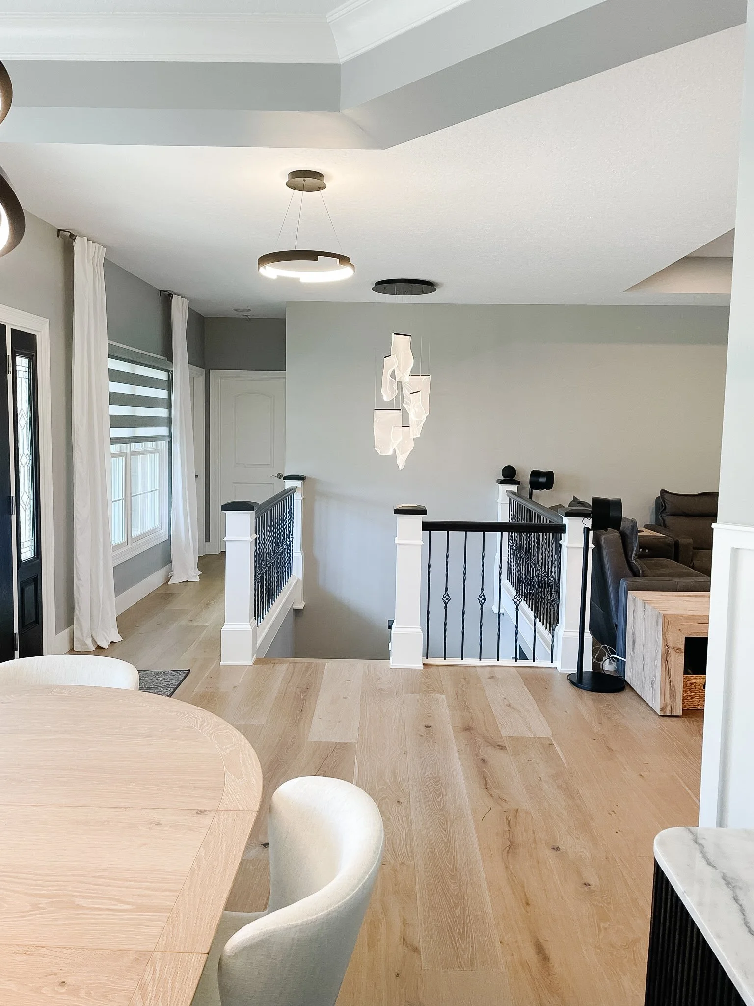 Open-concept living area with light wood flooring, a sculptural pendant light, and an updated open stairway railing in a Xenia, Ohio home