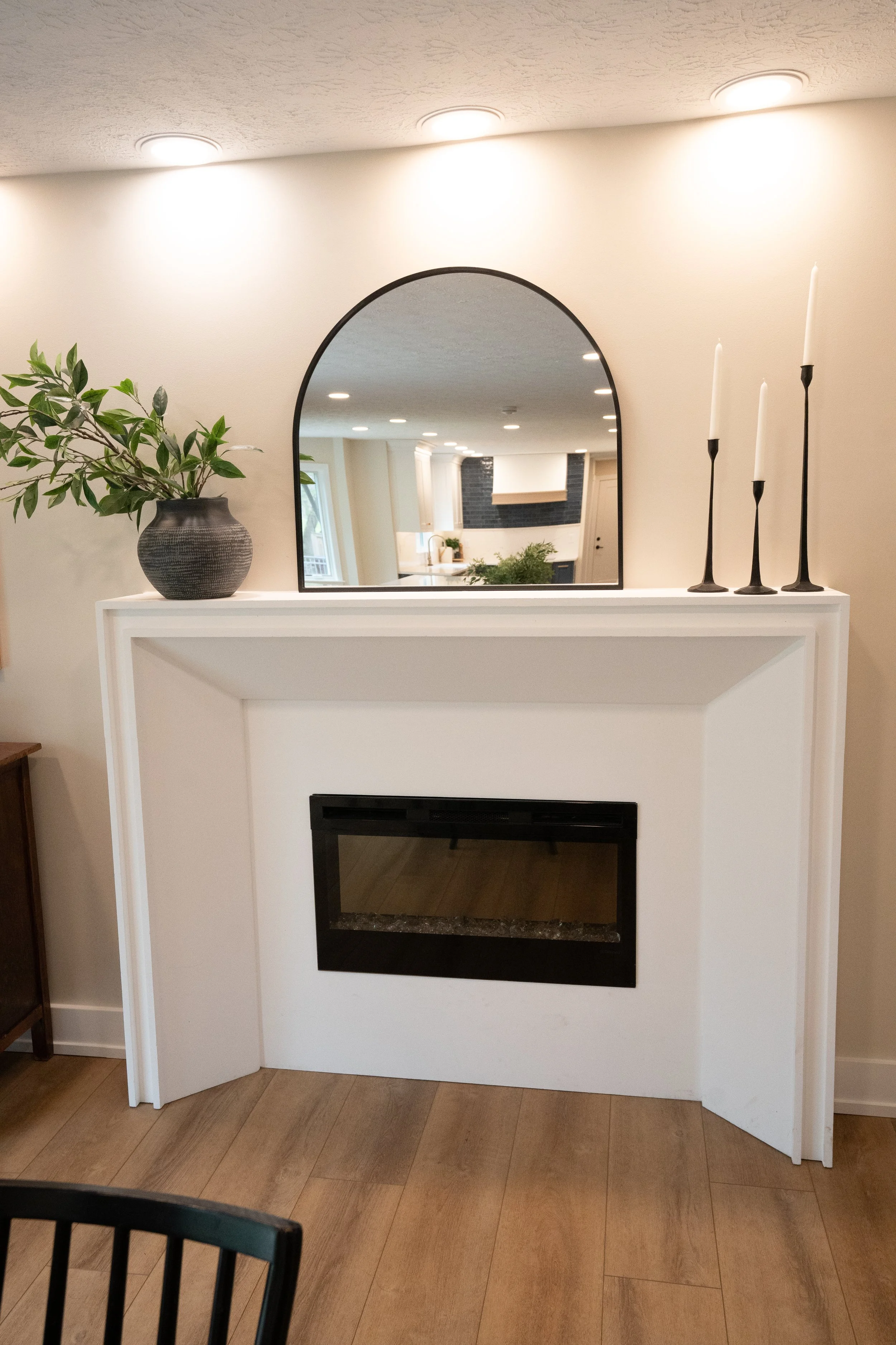 Custom angled fireplace surround with a linear electric fireplace and arched mirror above the mantel in a Centerville whole-home remodel.