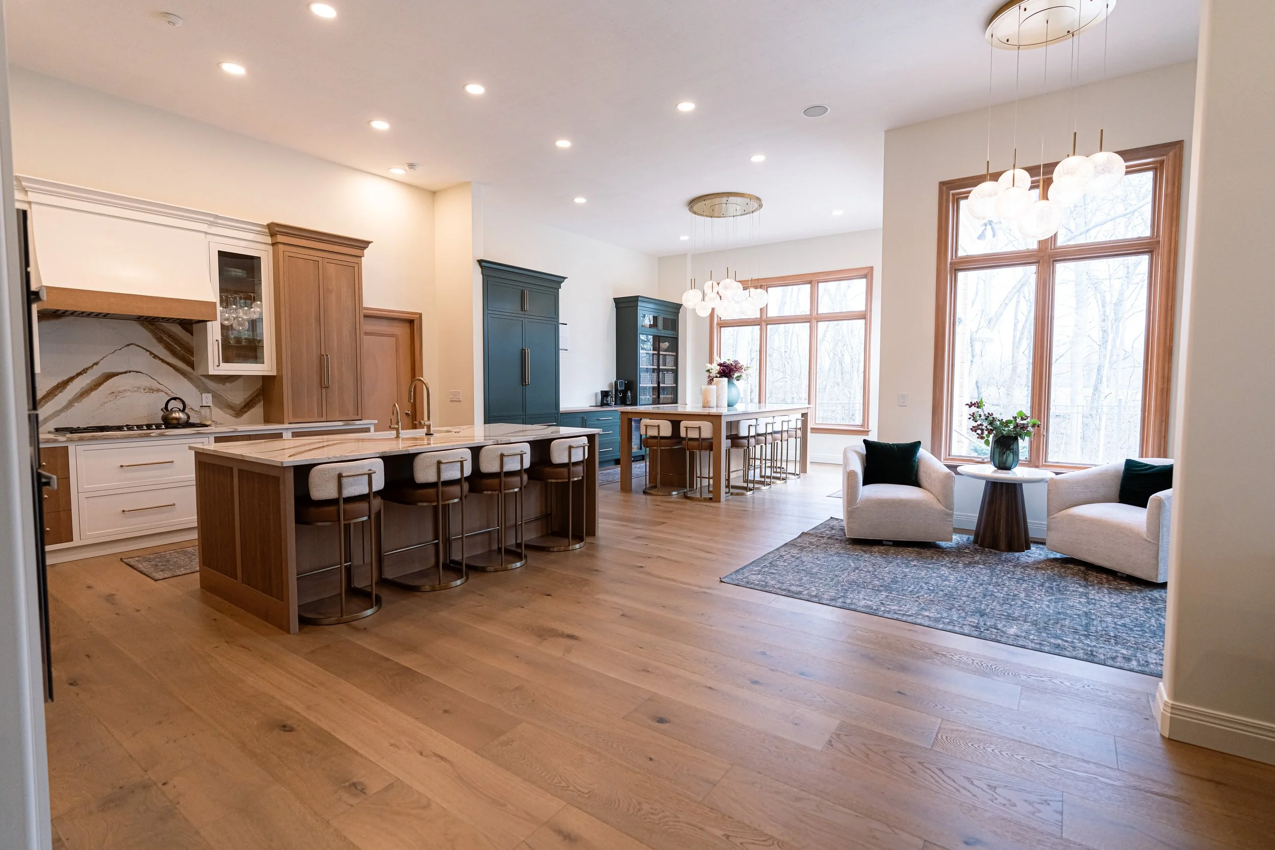 Open-concept Bellbrook, Ohio whole-home remodel with kitchen island, dining table, green cabinetry, and living area by White Oak Interiors