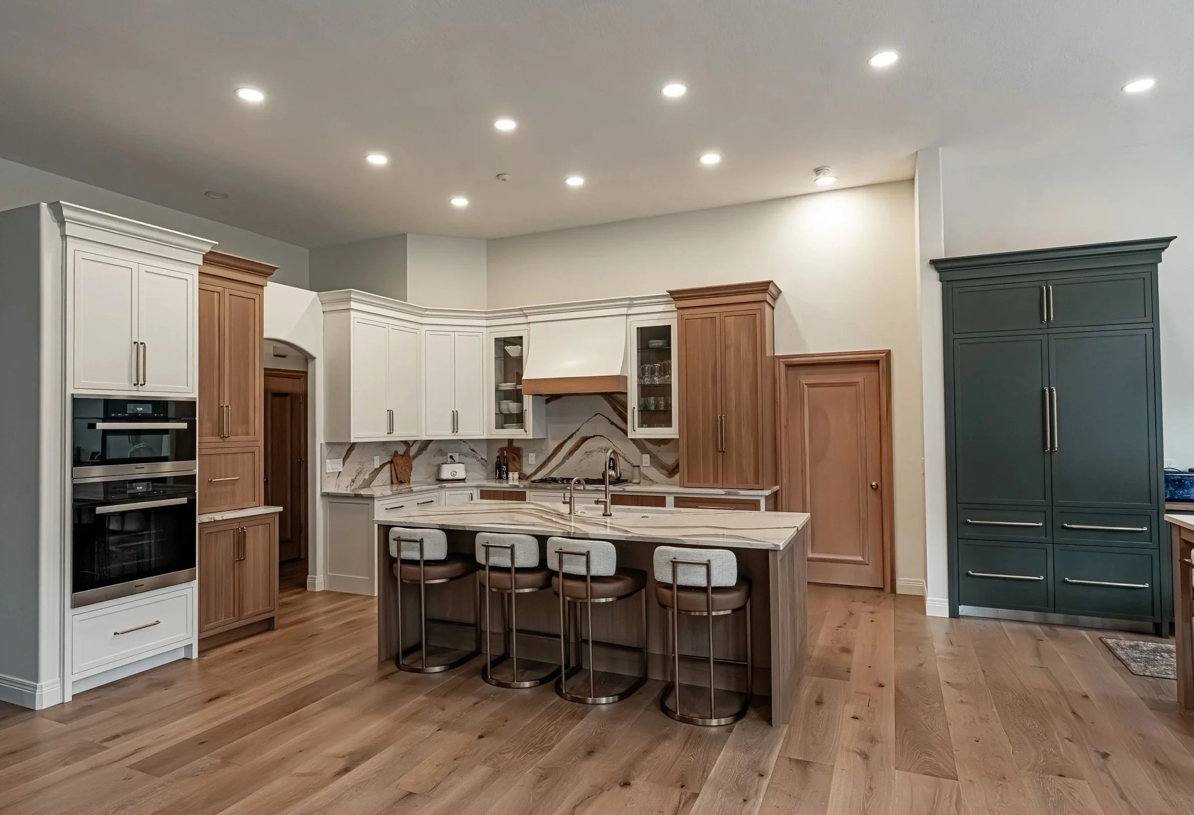 Kitchen with white and wood-tone cabinetry and an island with counter stools, designed by White Oak Interiors in the Dayton, Ohio area.