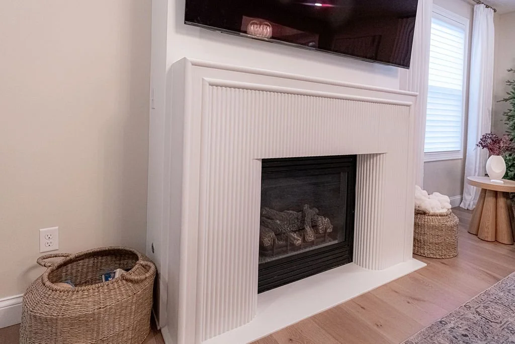 Custom-designed white concrete fireplace with a fluted surround and mounted television in an Oakwood, Ohio living room renovation