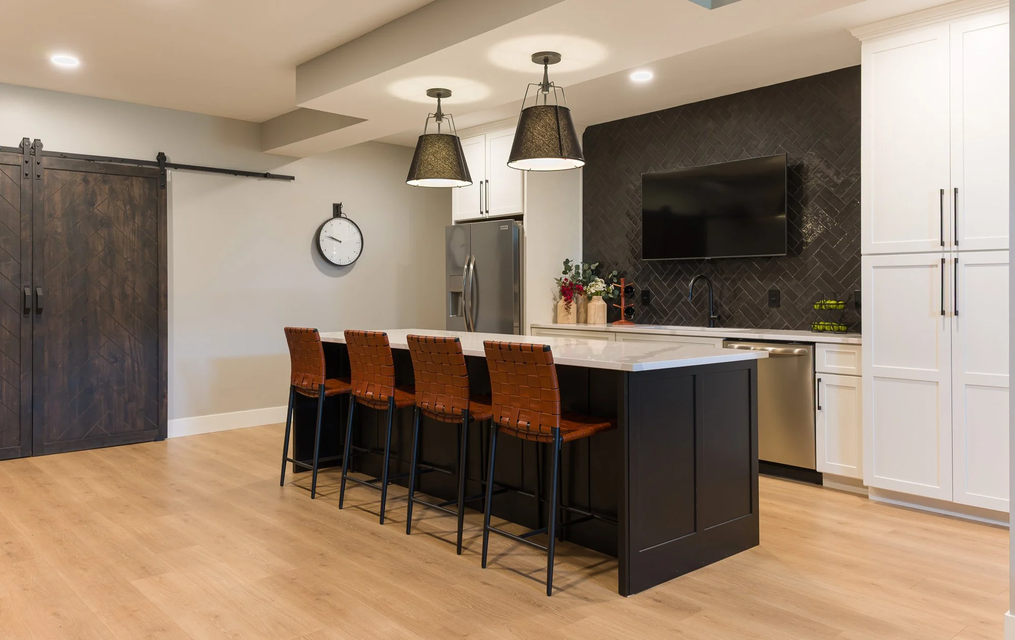 Finished basement kitchen with black island, leather barstools, and herringbone accent wall in Beavercreek, Ohio