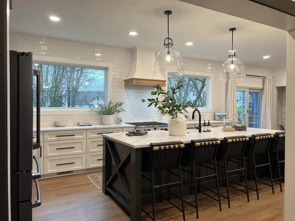Spacious renovated kitchen with white perimeter cabinetry, a green X-detail island, glass pendant lights, and a custom range hood in a Springboro, Ohio home
