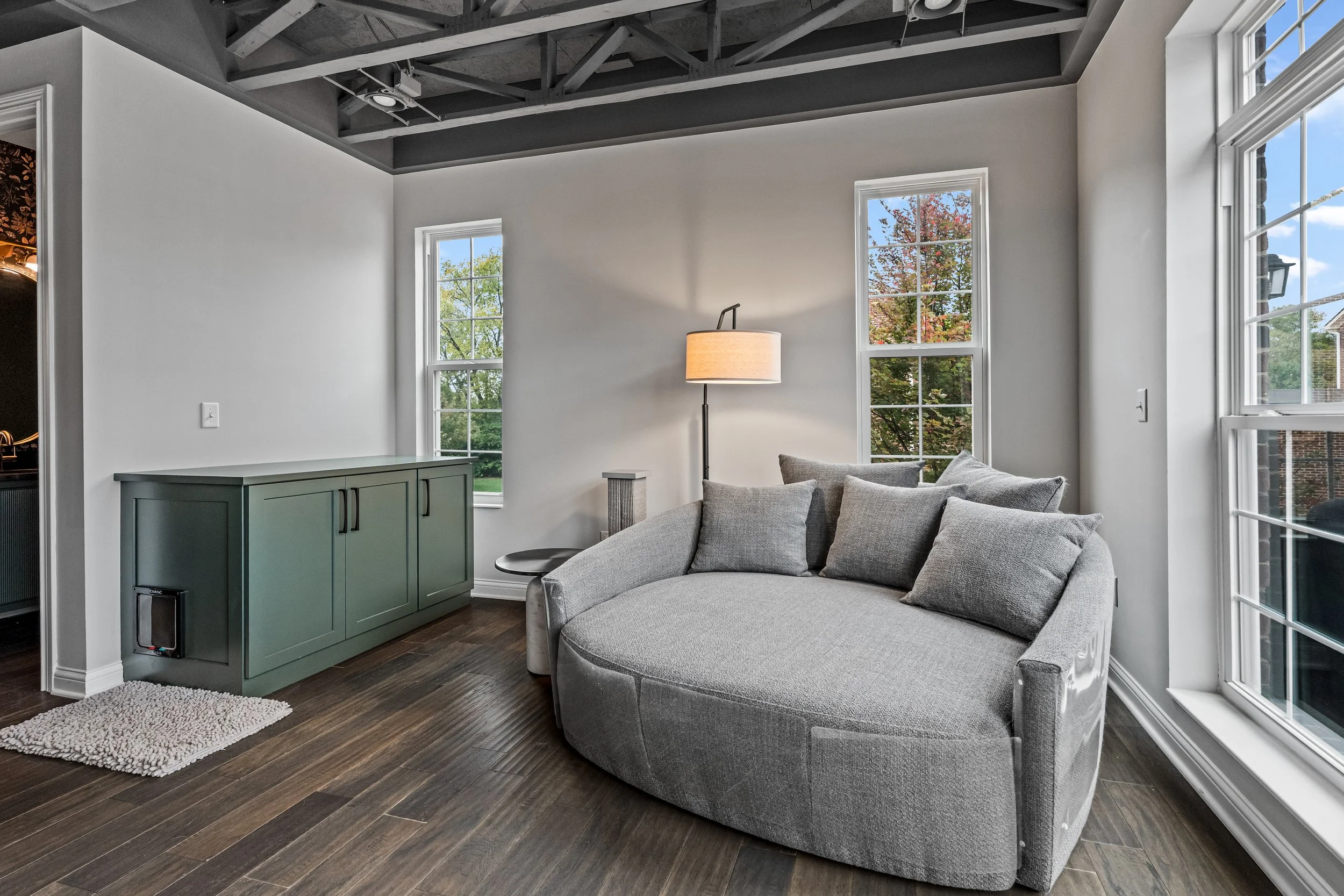 Cozy reading nook in Springboro, Ohio with a curved sofa, green built-in cabinet, and natural light by White Oak Interiors