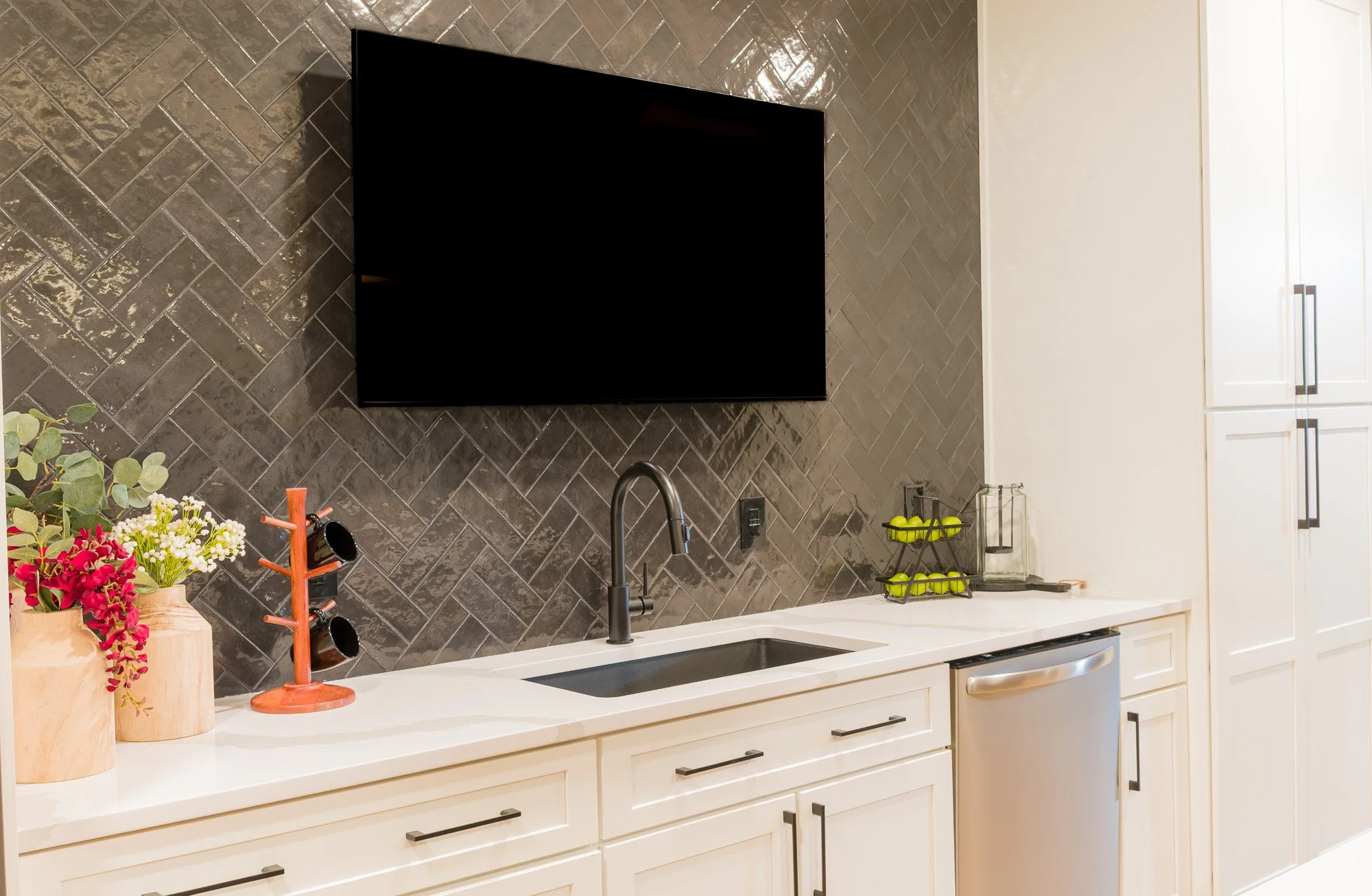 Black sink and faucet against a gray herringbone backsplash in a custom basement kitchen near Dayton, Ohio
