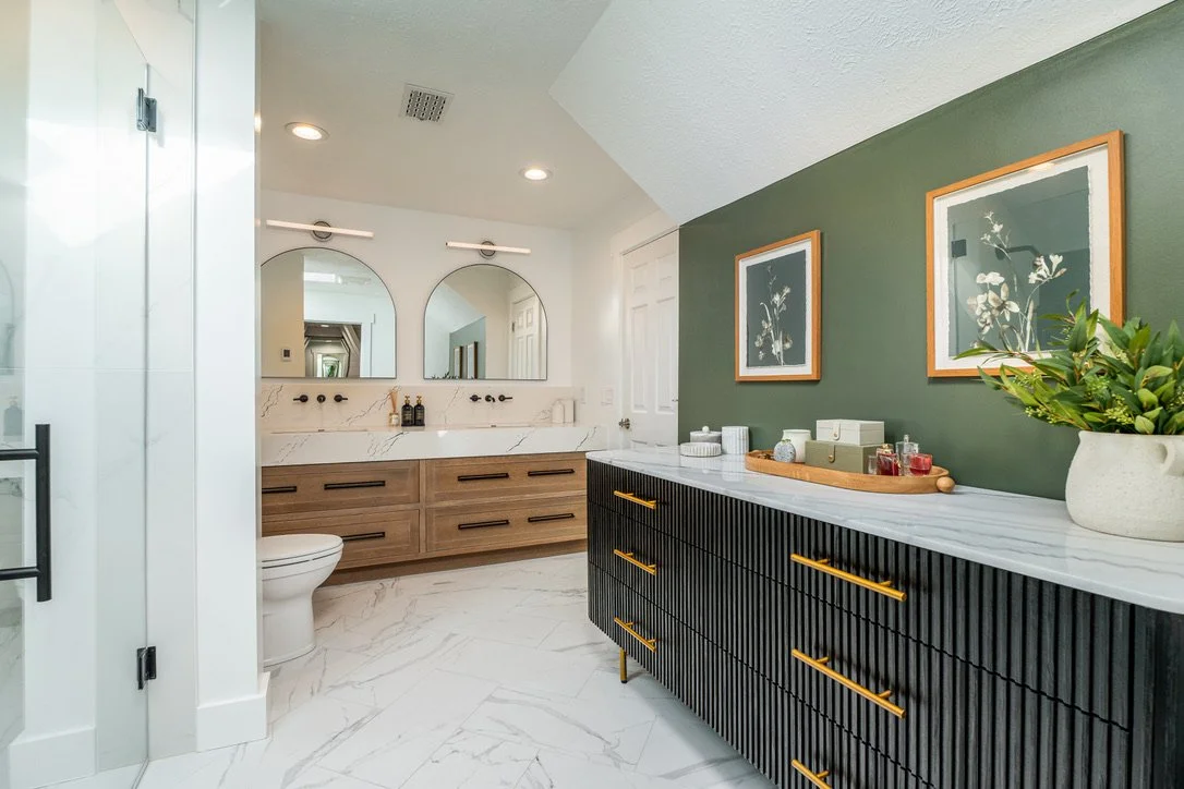 Master bathroom renovation in the Dayton, Ohio area with a fluted black double vanity, olive-green walls, arched mirrors, and brass fixtures by White Oak Interiors