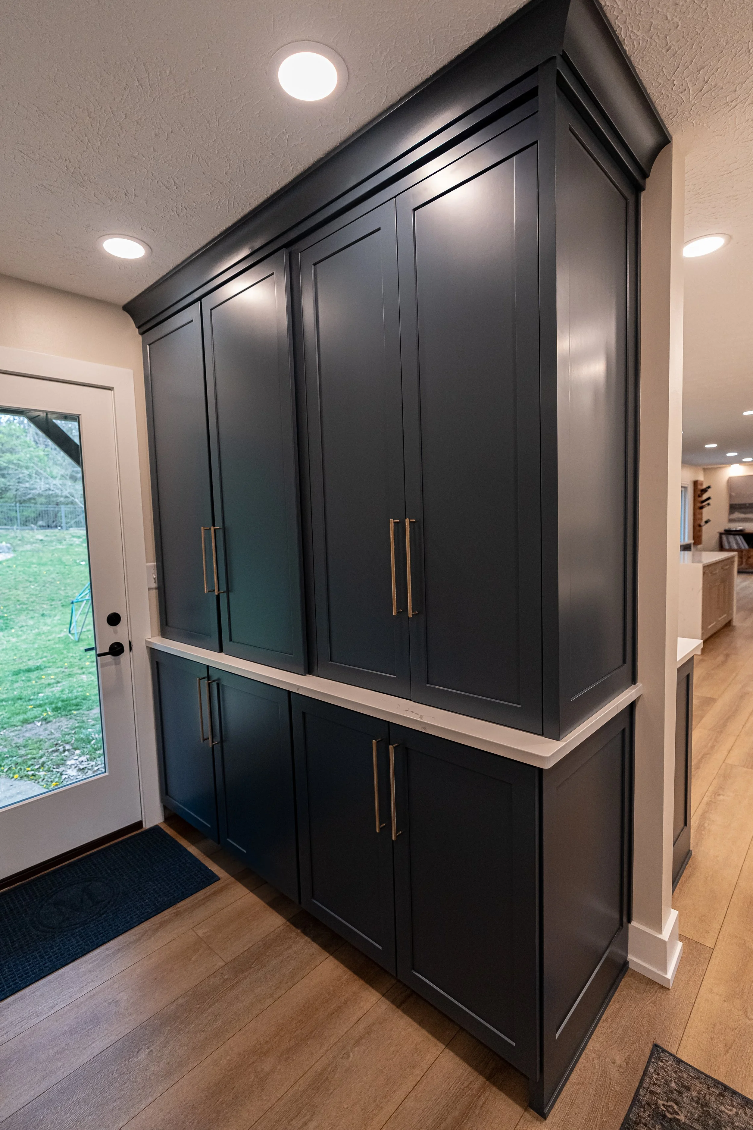 Butler pantry with floor-to-ceiling navy cabinetry, brass hardware, and a light wood counter in a Centerville whole-home remodel.