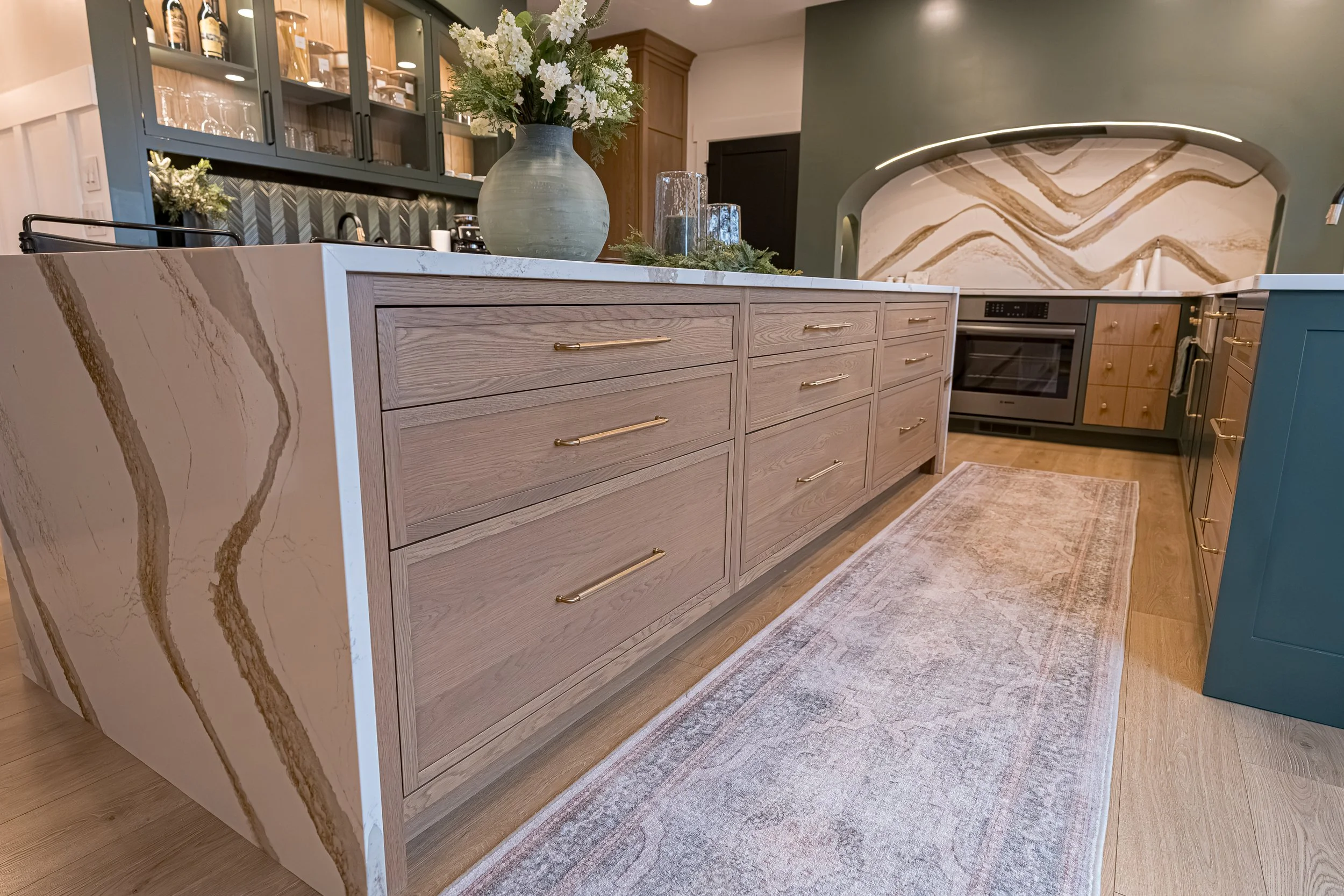 Custom white oak kitchen island with brass pulls and Cambria quartz waterfall countertop