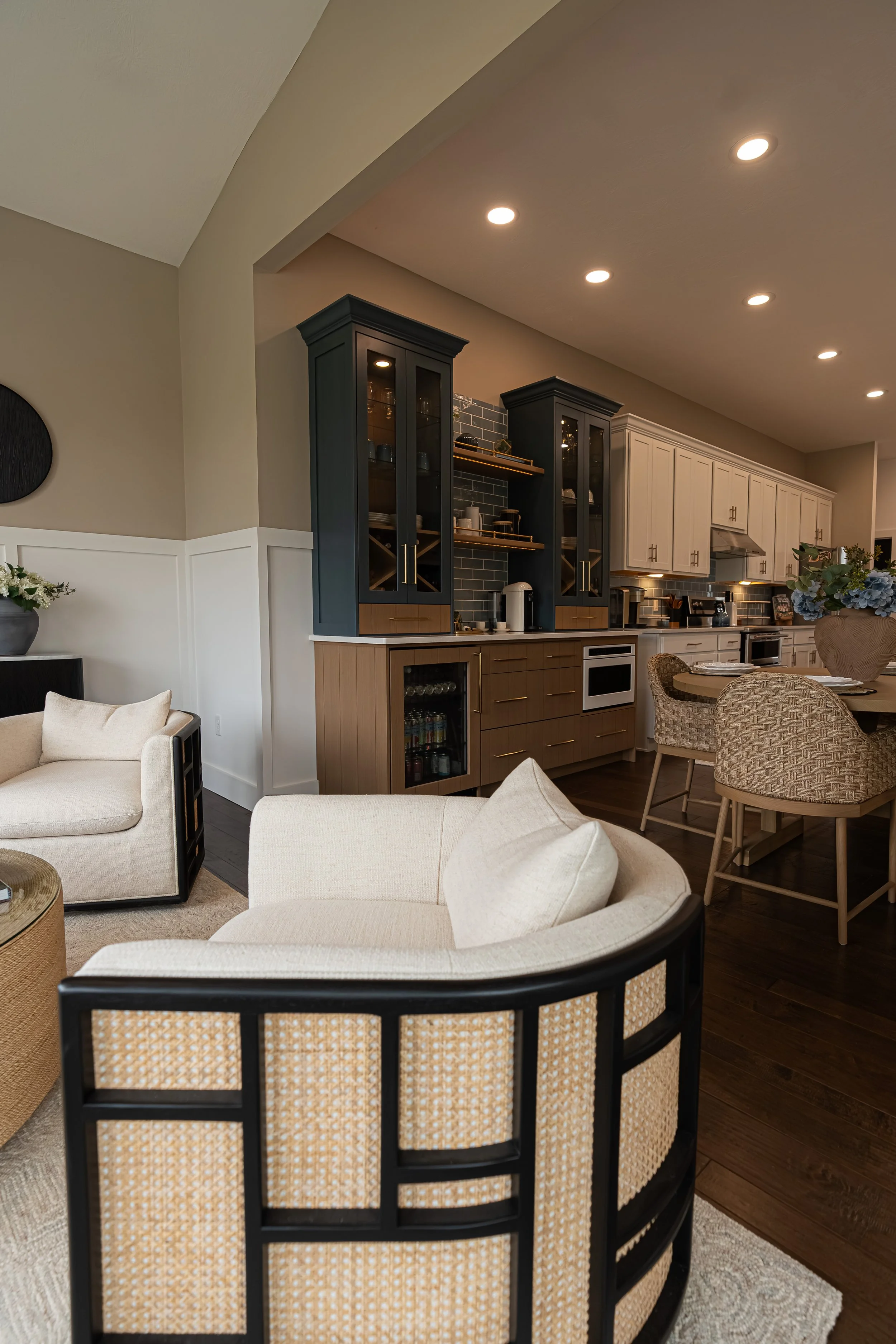 Formal sitting room with a curved cream-and-cane sofa opening through to the navy-and-white kitchen in a Centerville home renovation.