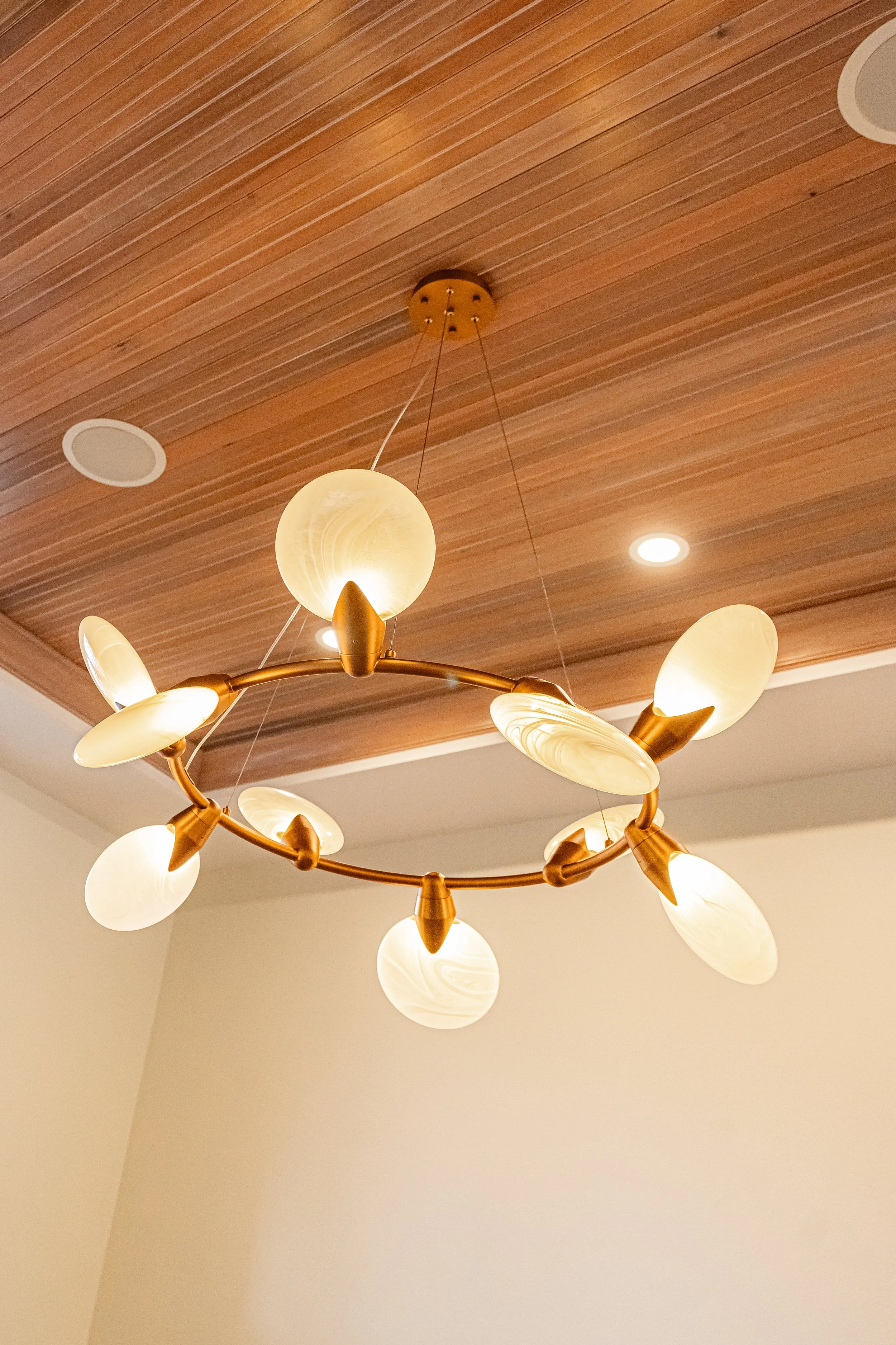 Modern brass-and-glass chandelier mounted on a wood-slatted tray ceiling in a Bellbrook lounge room.