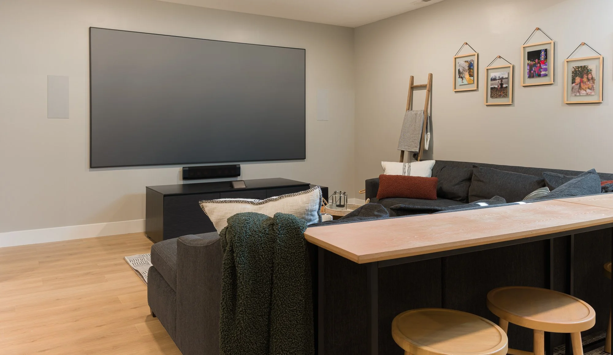 Basement media zone with a projection TV, sectional seating, and adjacent dining table in Beavercreek, Ohio