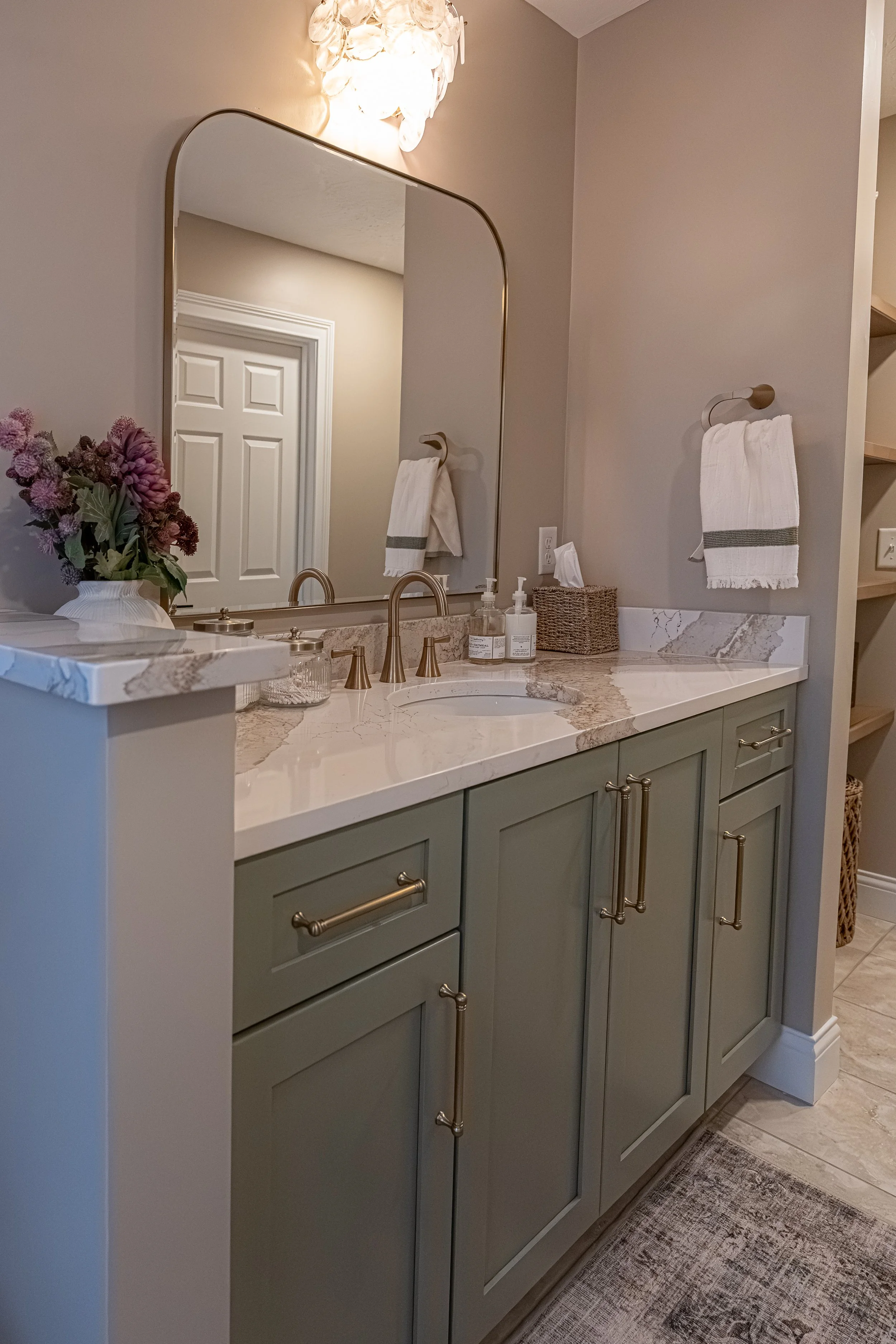 Guest bathroom with green cabinetry, quartz countertop, brushed gold faucet and hardware, and an arched mirror in an Oakwood, Ohio renovation
