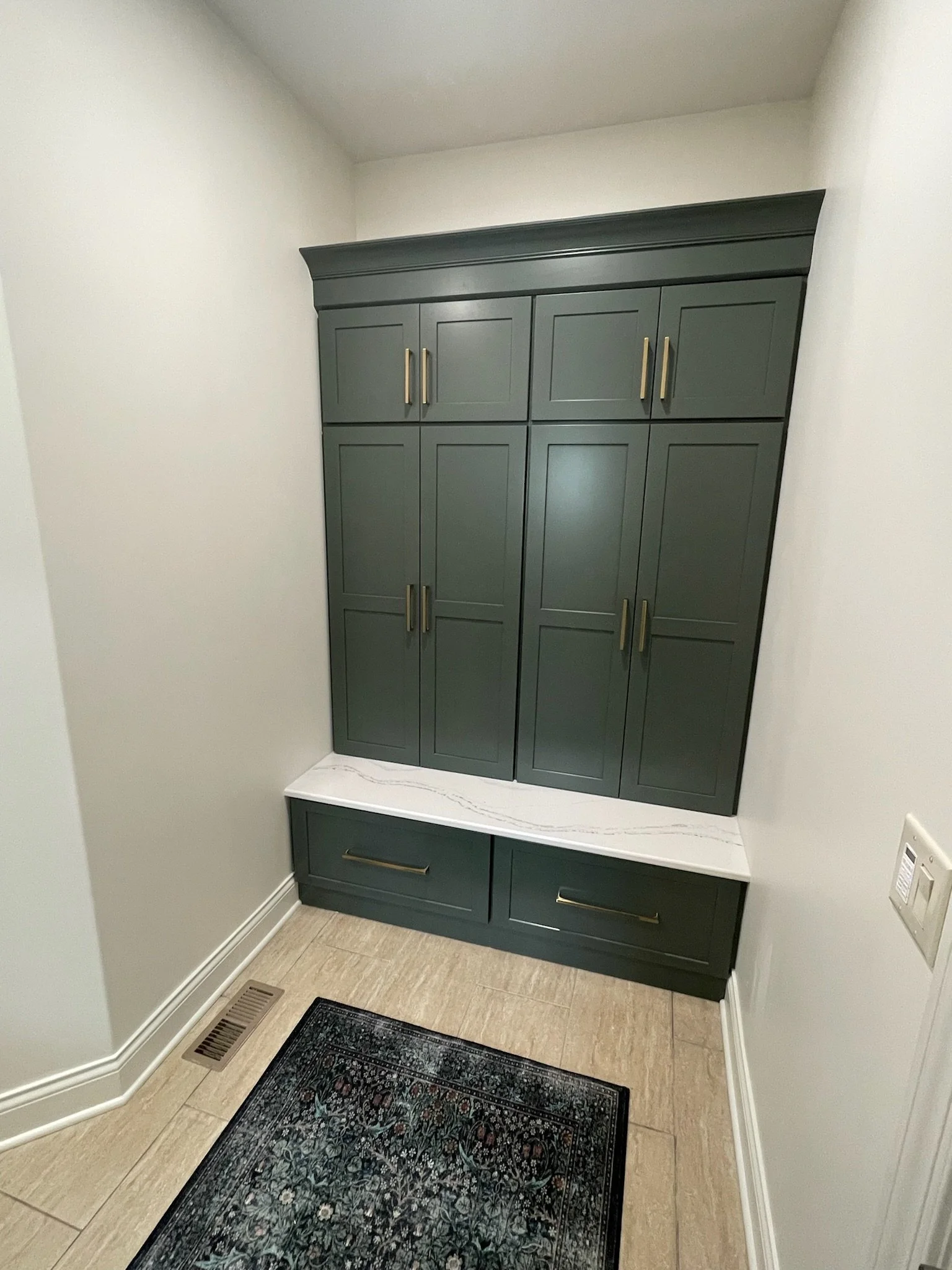 Mudroom nook with floor-to-ceiling green cabinetry, a quartz bench seat, and built-in storage drawers in a Beavercreek, Ohio home