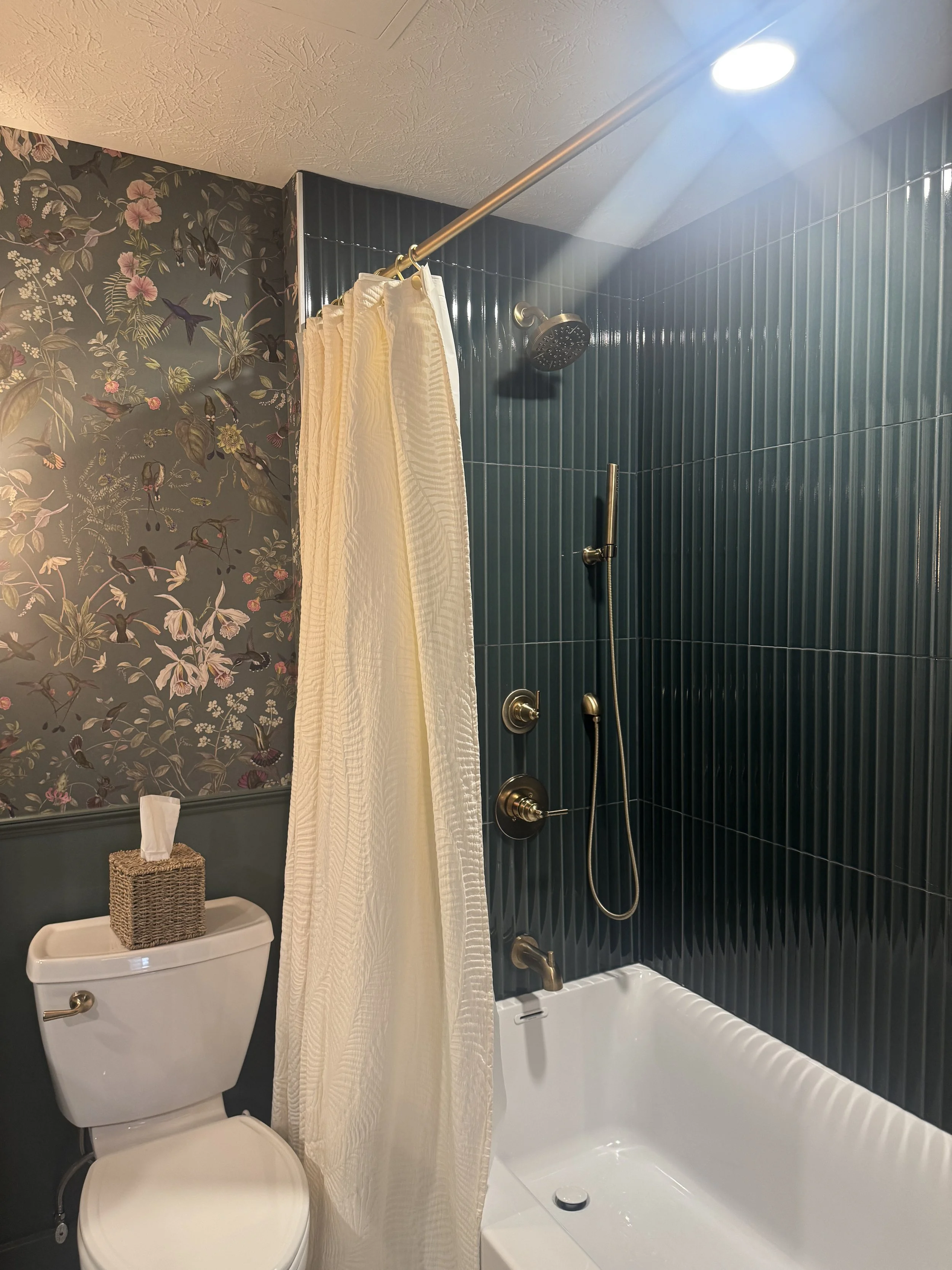 Beavercreek, Ohio basement bathroom renovation with a green fluted tile shower surround, new tub, and brass fixtures by White Oak Interiors