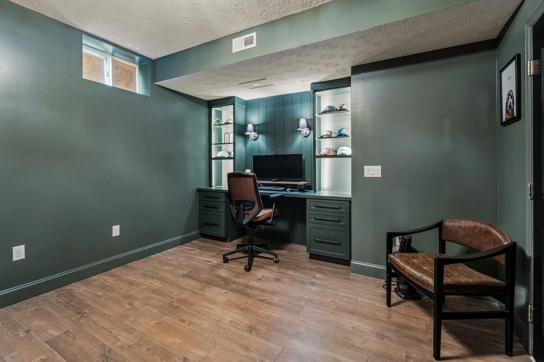 Basement home office with green built-in desk and shelving in a Brookville, Ohio basement renovation.