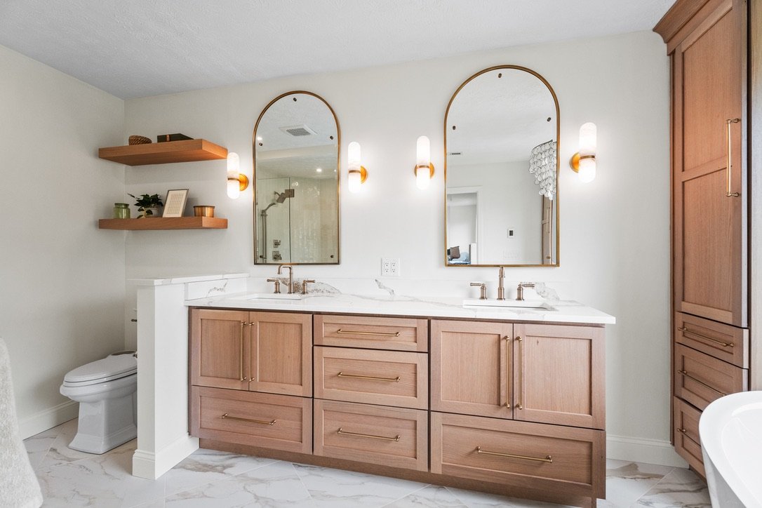 Master bathroom double vanity with wood cabinetry, marble countertop, arched mirrors, and brass sconces in a Brookville, Ohio bathroom renovation.