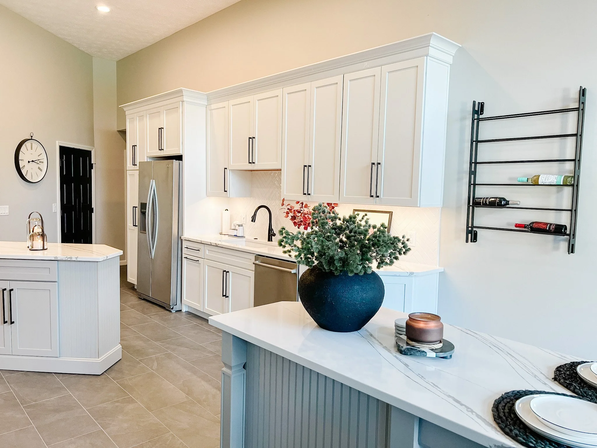 Open white kitchen with an island, an eat-in counter with seating, marble-look surfaces, and stainless appliances in a Centerville, Ohio home