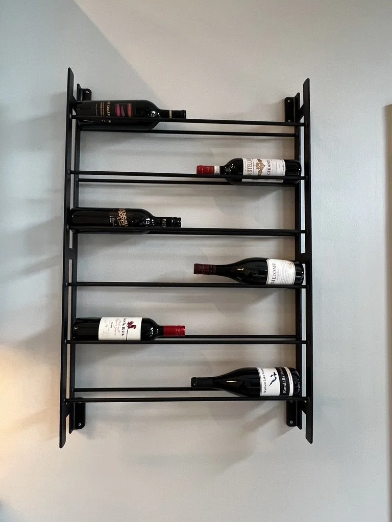 Black wall-mounted horizontal wine rack displaying bottles in a Centerville, Ohio home
