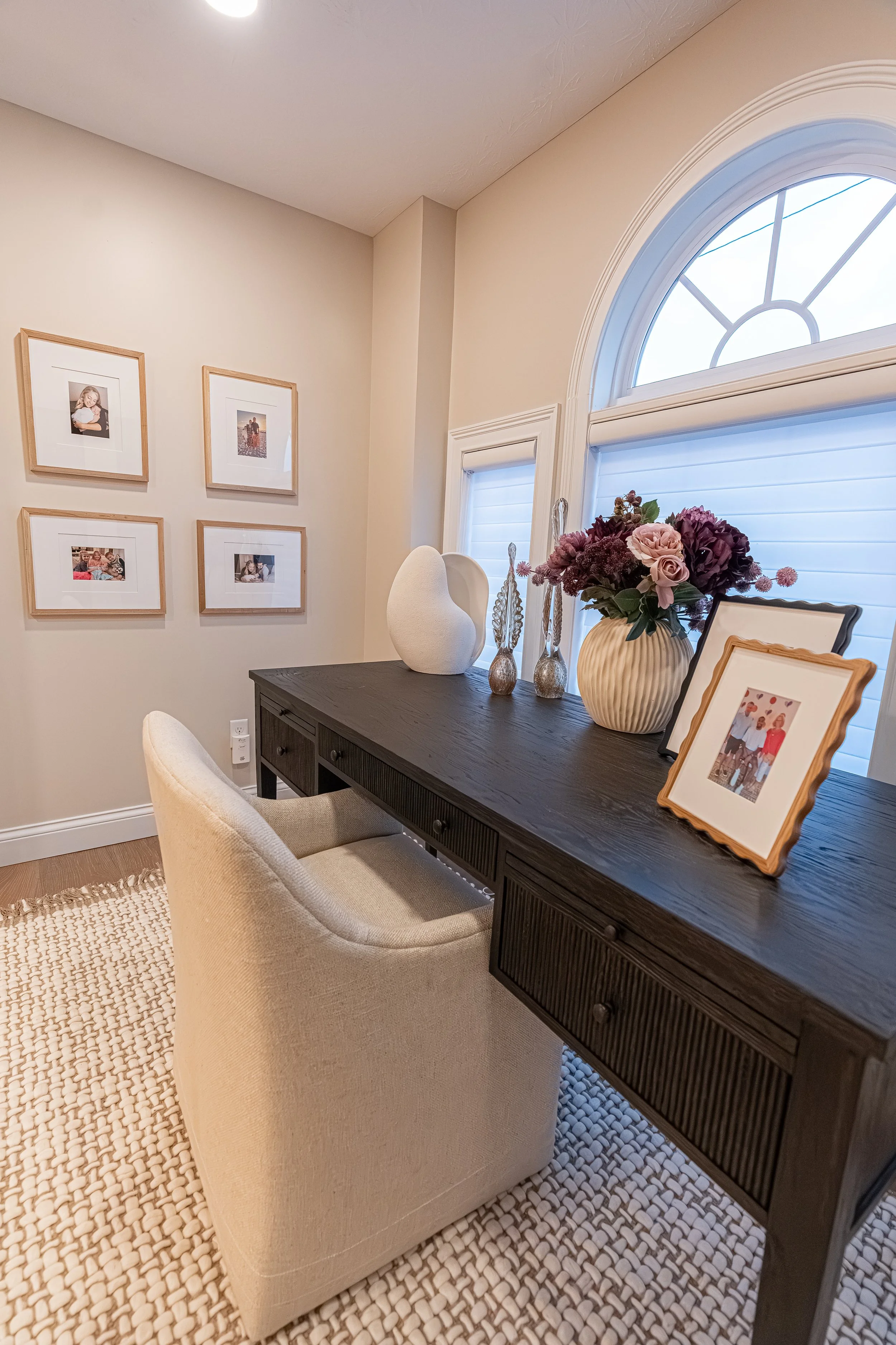 Office loft with a black reeded desk, upholstered chair, framed gallery wall, and an arched window in an Oakwood, Ohio home
