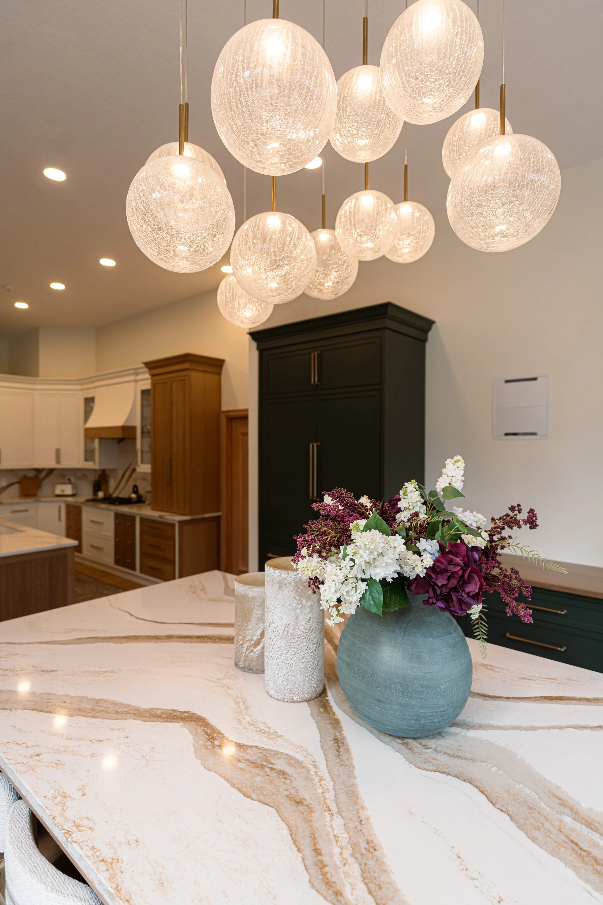 Gold-veined marble countertop beneath a statement glass globe chandelier in a Bellbrook, Ohio kitchen remodel