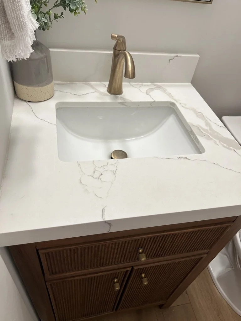 Half bath detail with a reeded wood vanity, veined quartz countertop, undermount sink, and gold faucet in a Springboro, Ohio home