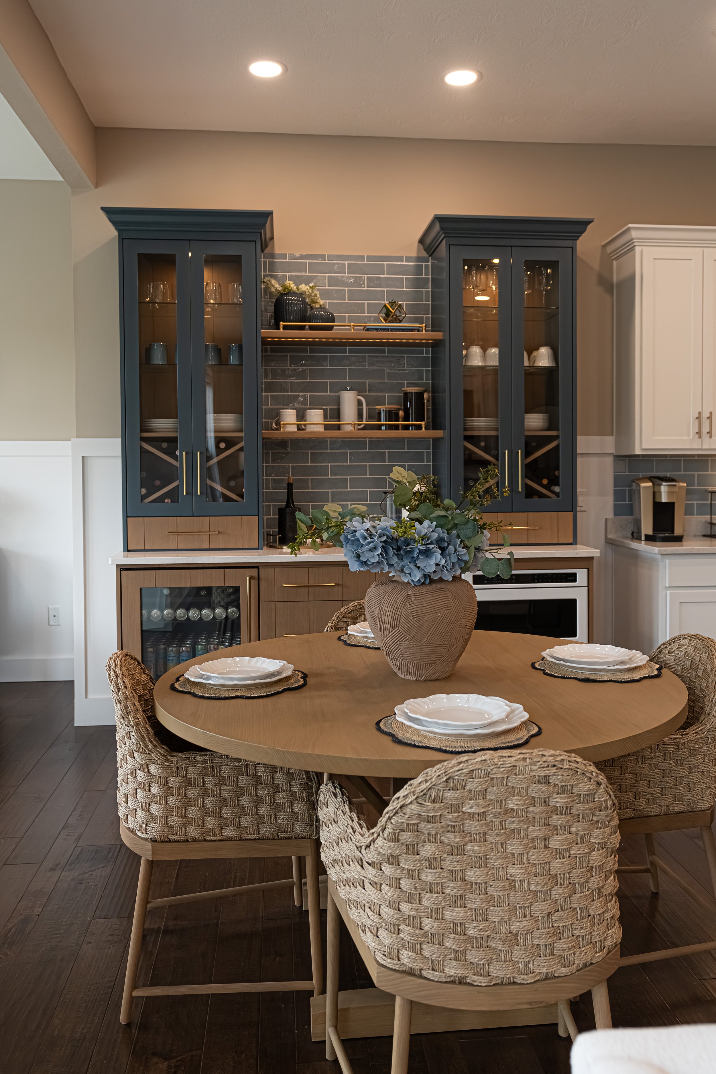 Coffee bar and breakfast nook with navy cabinetry, a round wood table, and woven chairs in a Centerville home renovation.
