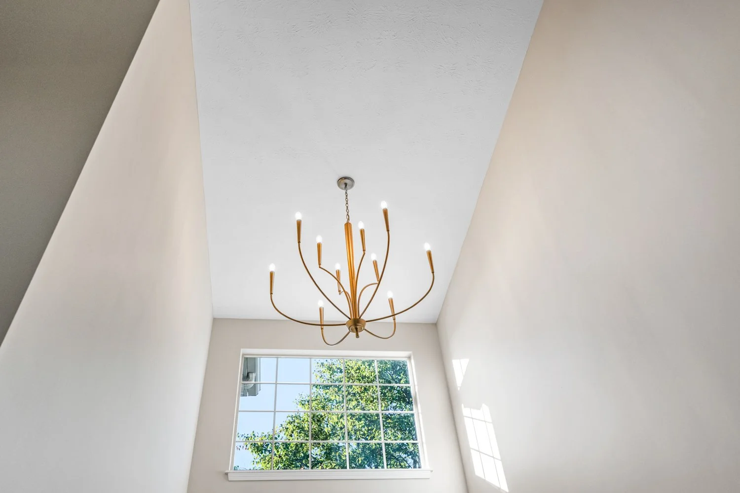 Two-story entry foyer with a brass chandelier and tall grid window in a Beavercreek, Ohio main-level remodel.