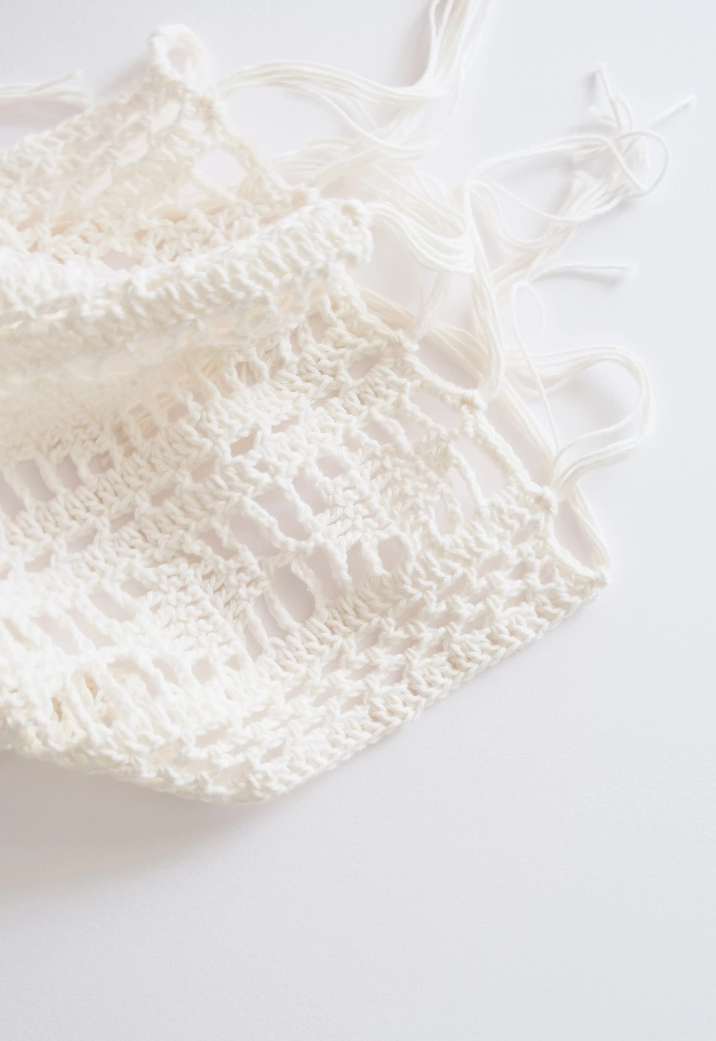 Close-up of white crochet lace table runner on a white surface.