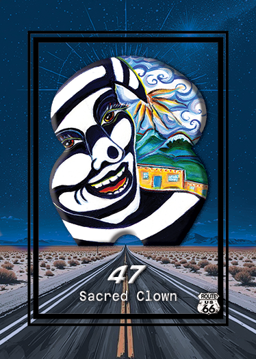 A painted mural featuring a clown face with black and white stripes, a rainbow, mountains, a building, and the Route 66 sign, framed by a starry night sky.