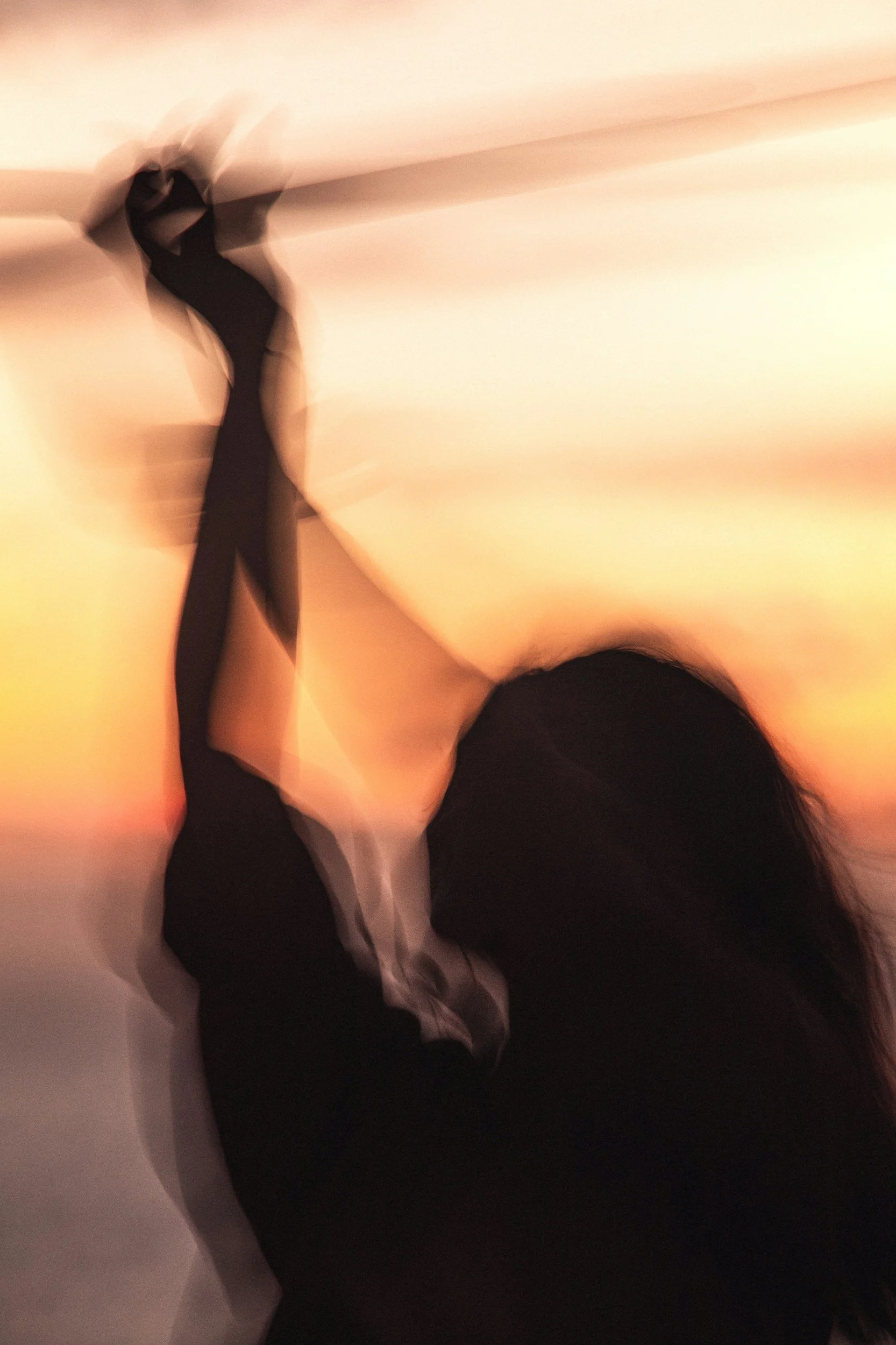 A person holding a long object against a sunset sky, with motion blur.