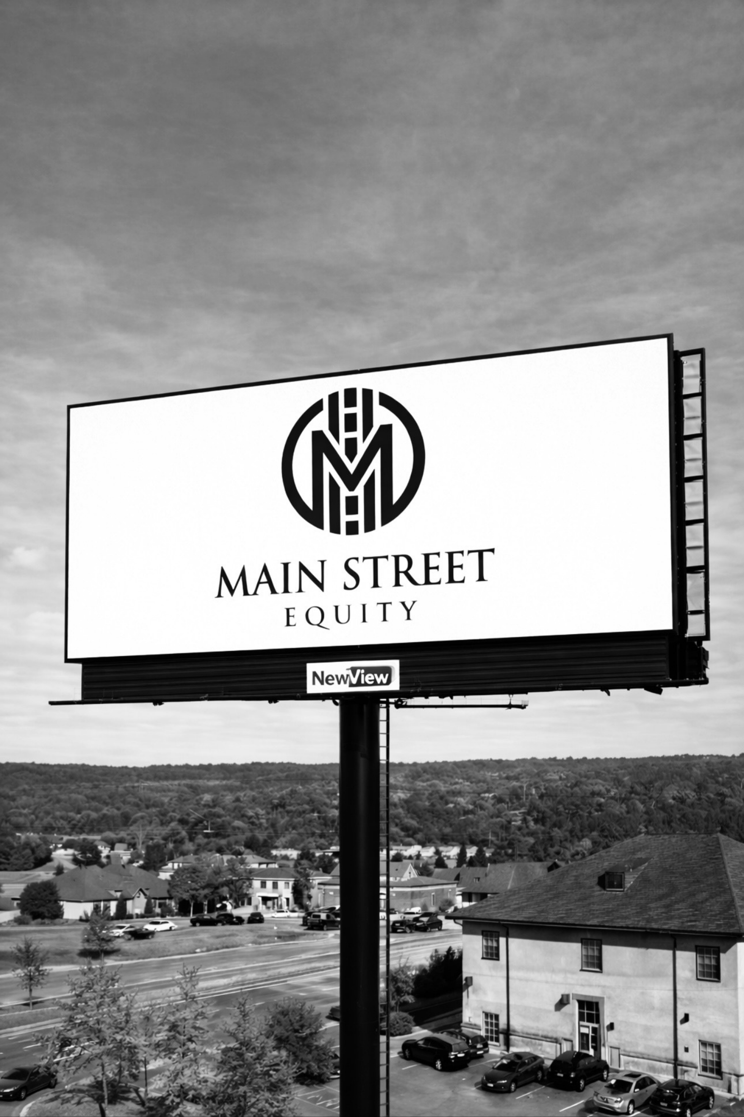 Black and white image of a billboard advertising Main Street Equity with a logo at the top, and a parking lot with cars, residential buildings, and trees in the background under a partly cloudy sky.