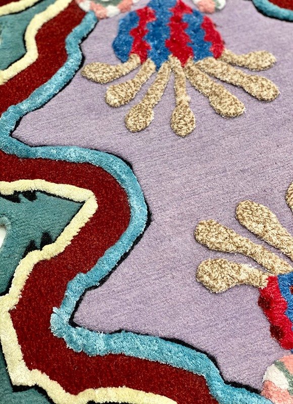 Close-up of a colorful decorative rug featuring lobster designs and abstract shapes on a purple background.