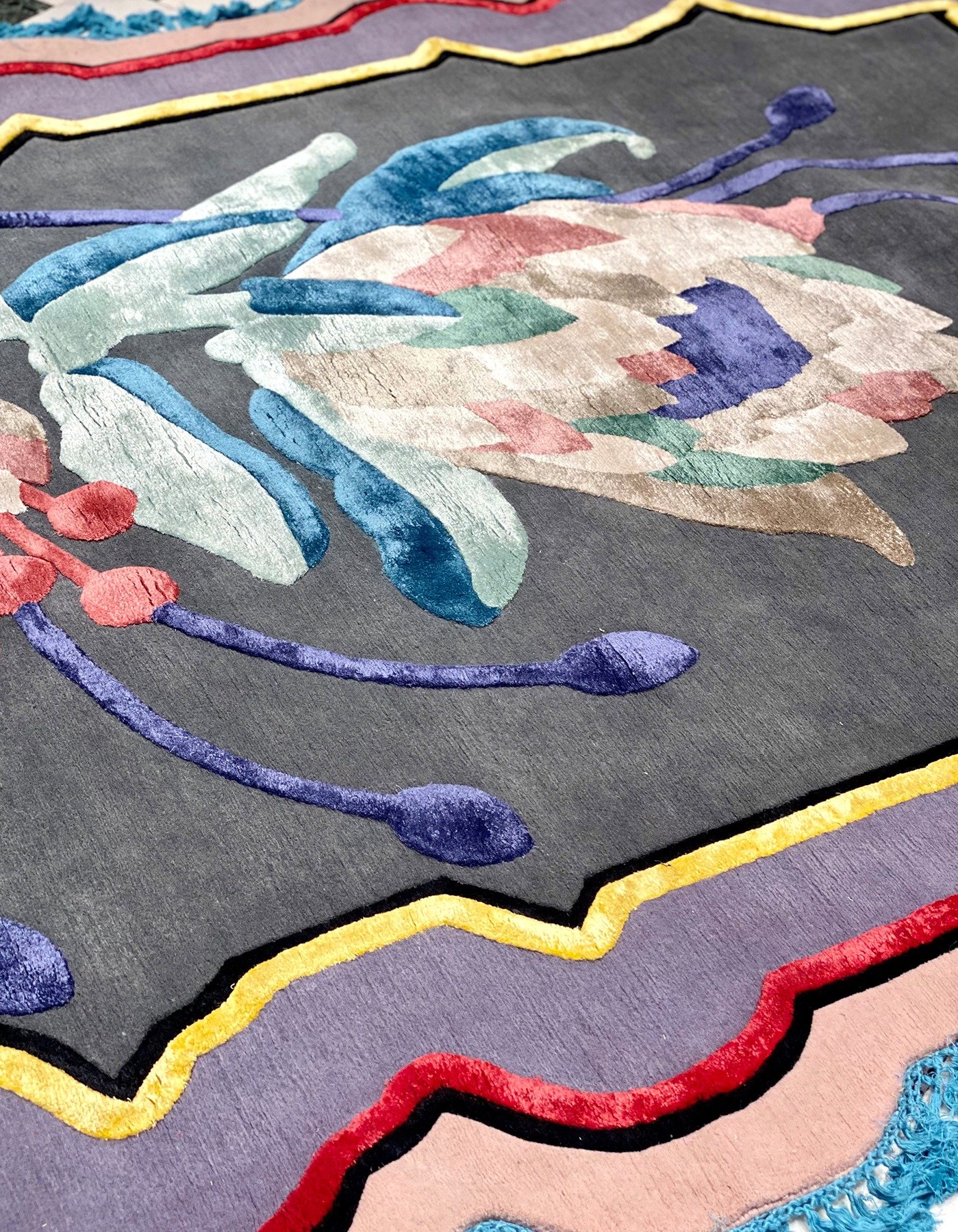 Close-up of embroidered floral design on dark fabric with colorful petals, leaves, and border.