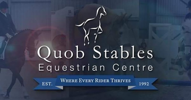 Sign for Quob Stables Equestrian Centre, established in 1992, with a horse logo and a background of children riding horses.