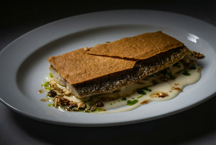 white plate topped with cream based sauce and crispy fish with delicate shell top