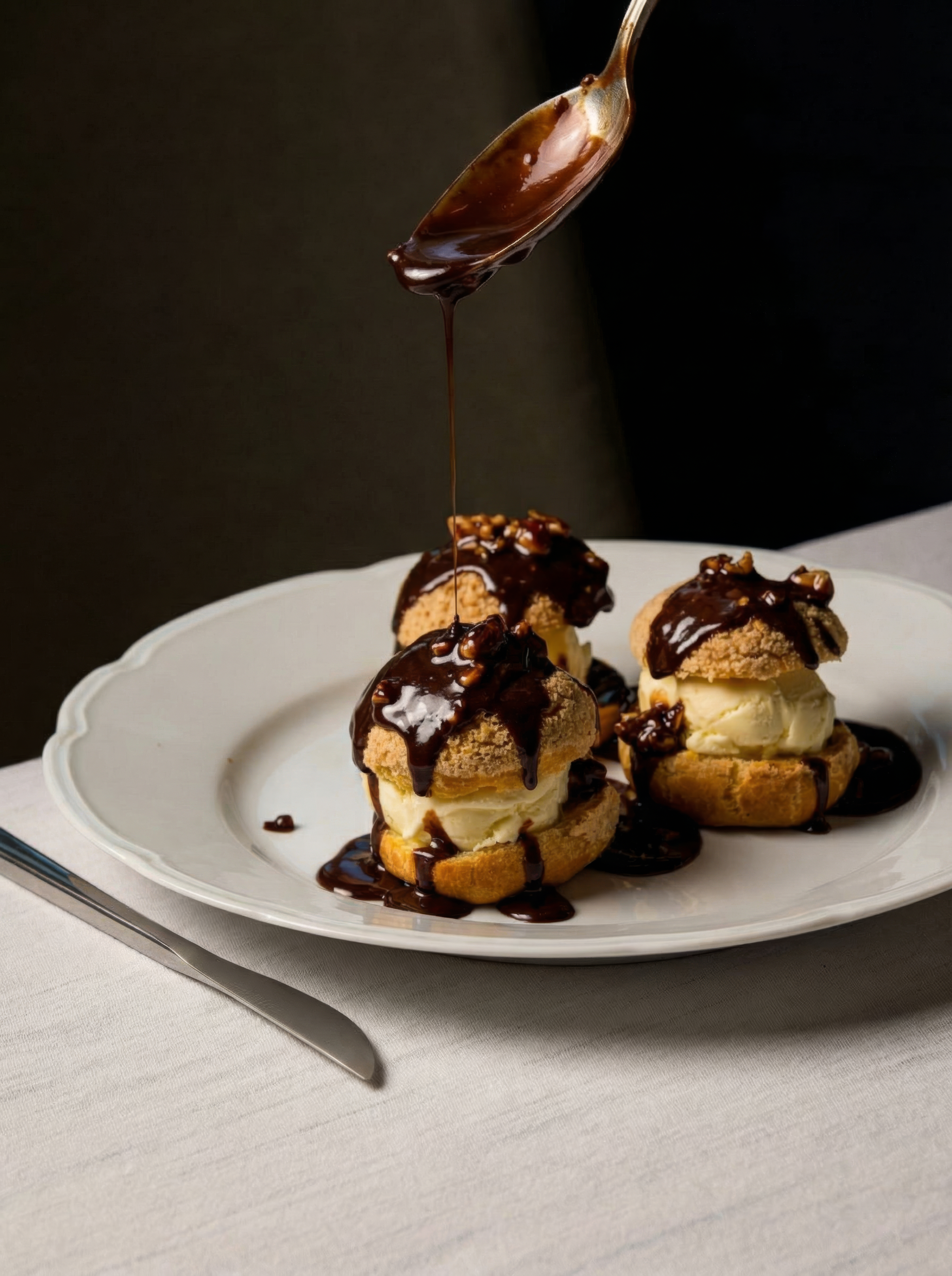 3 creampuff pastry on a white plate with chocolate drizzle
