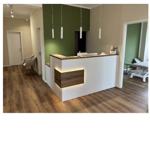 Modernes Empfangs- oder Rezeptionstresen in einer Praxis oder einem Büro mit Holz- und weißen Oberflächen, drei hängende Lampen, eine grüne Akzentwand im Hintergrund.