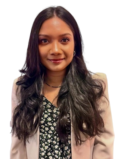 A young woman with long, wavy dark hair wearing a light-colored blazer over a black and white floral top, smiling at the camera.