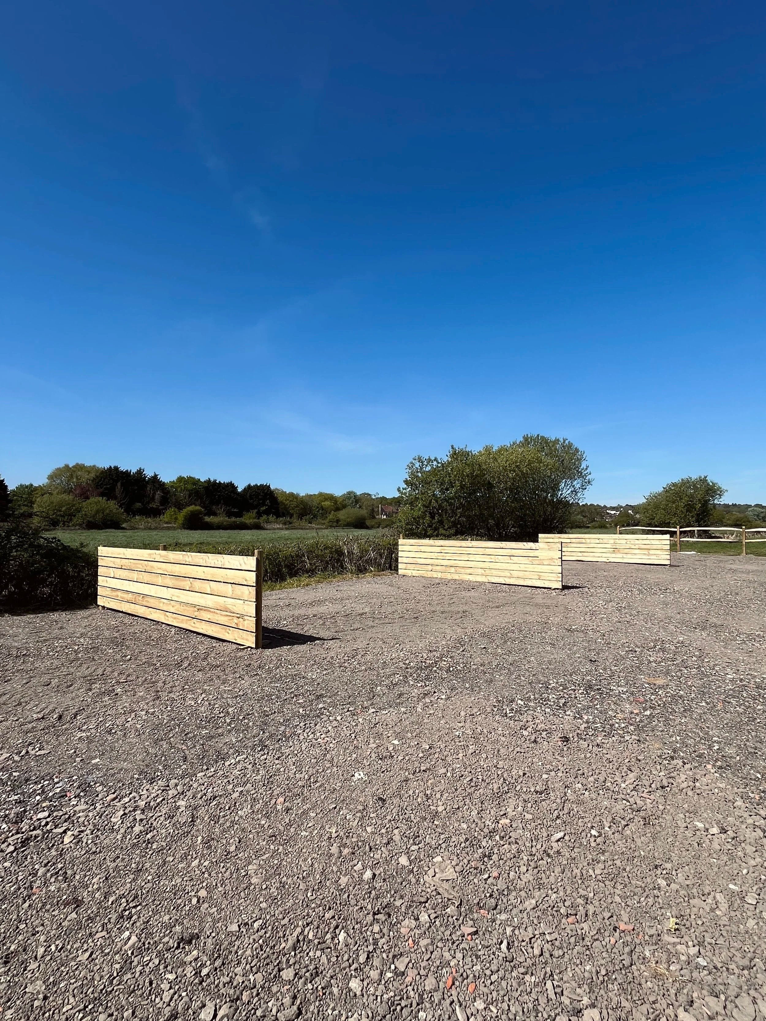 Hardstanding campervan site in Arundel, West Sussex.  They are divided with fences and surrounded by fields with the blue sky above