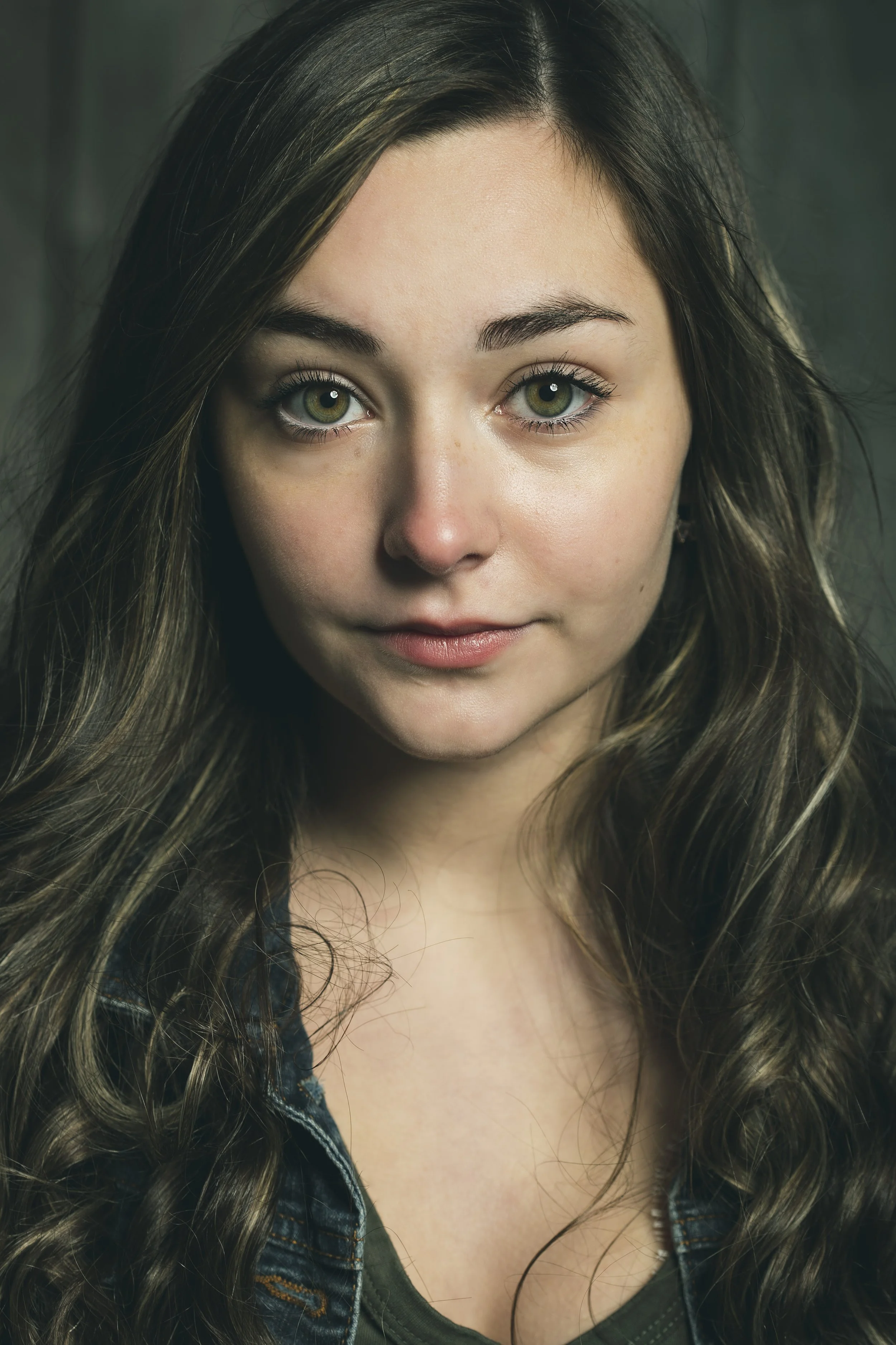 Close-up portrait of a young woman with long wavy hair, green eyes, and a calm expression. BoldVision Studios