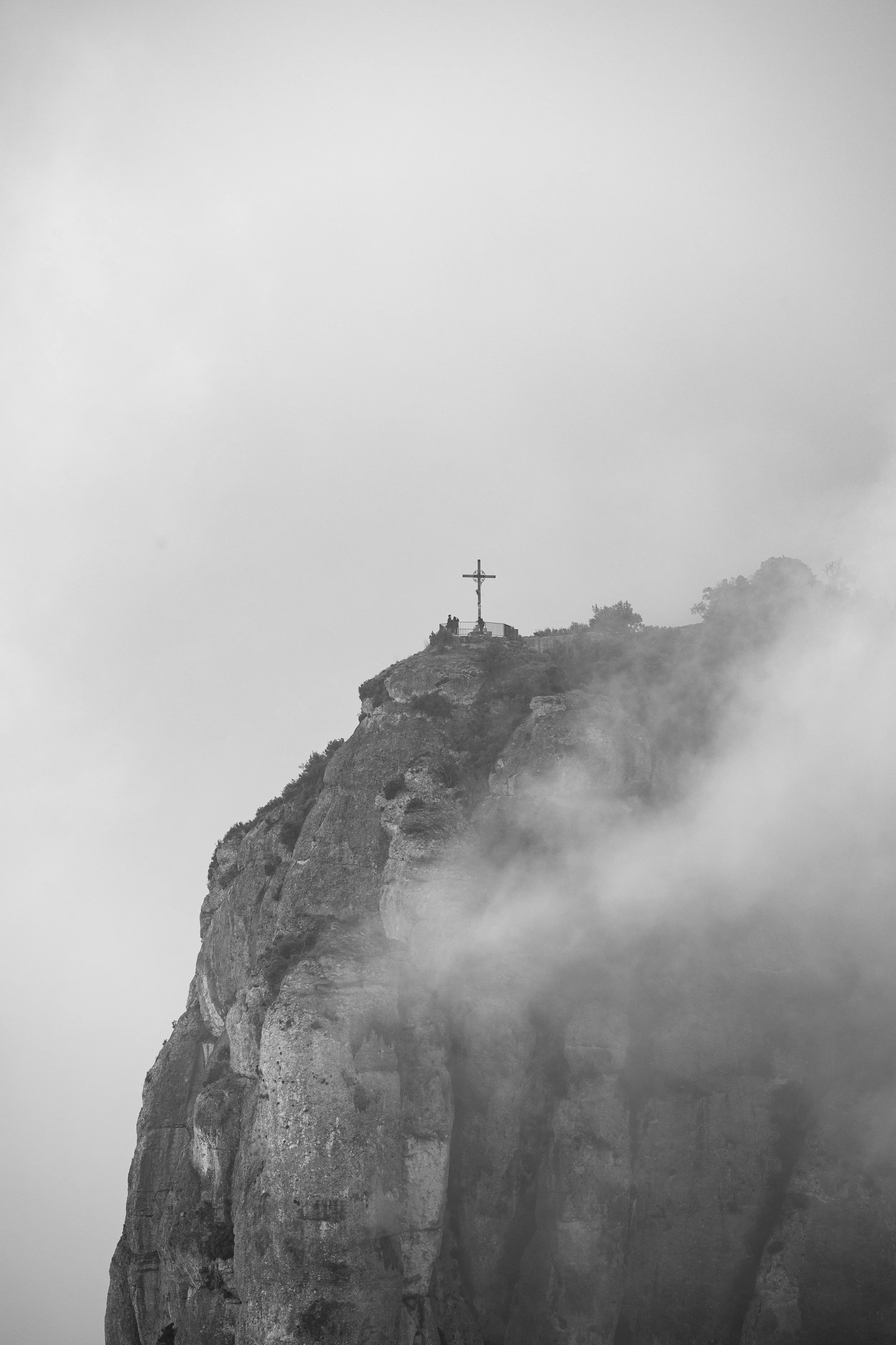 Black and white photo of a mountain with a cross on top, surrounded by fog. BoldVision Studios