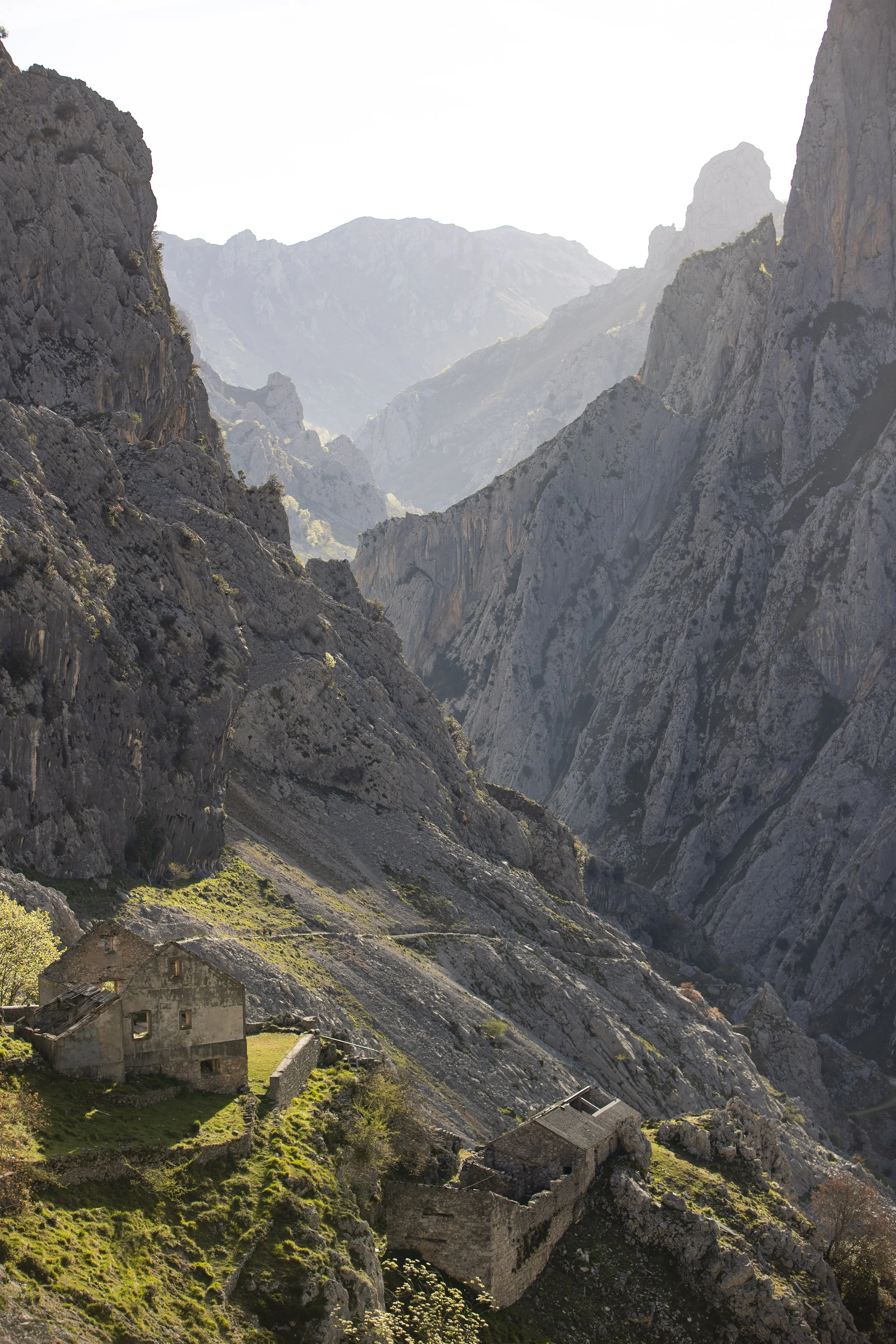 Ancient stone houses on a hillside in a rugged mountain landscape with steep cliffs and deep valleys. BoldVision Studios
