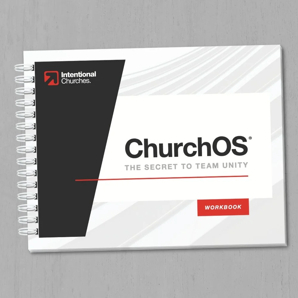 Cover of a workbook titled 'ChurchOS: The Secret to Team Unity' with a logo and the words 'Intentional Churches' on a spiral-bound book placed on a gray wooden surface.