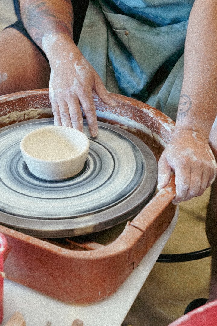 Person shaping clay on a pottery wheel in a pottery studio.